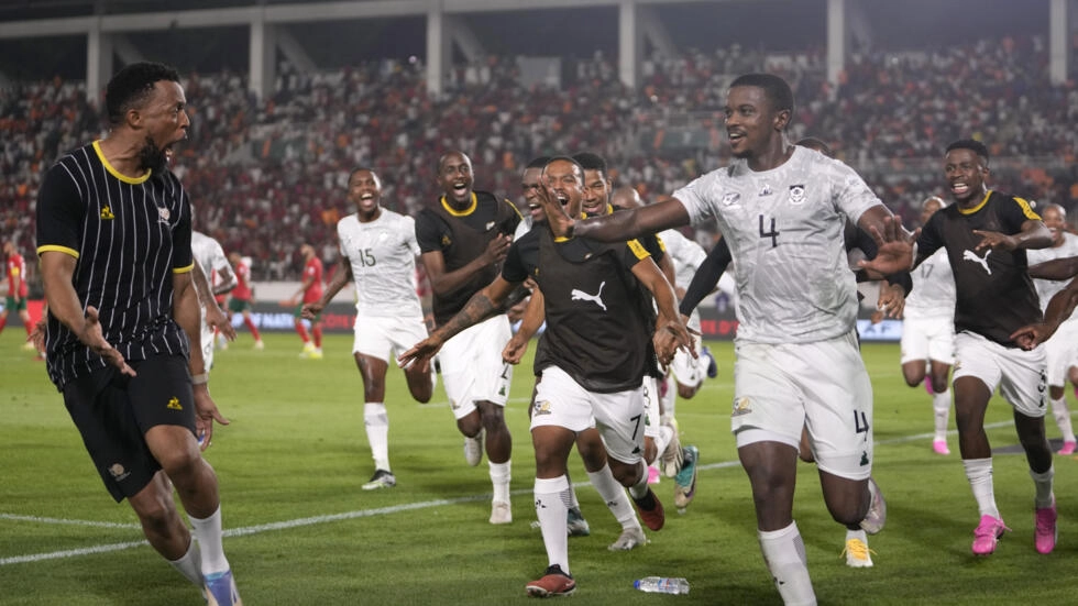 Image de Football. La Coupe d'Afrique des Nations (CAN) 2023 restera dans les mémoires comme un tournoi plein de surprises et de rebondissements inattendus. L'élimination du Maroc par l'Afrique du Sud en huitièmes de finale en est un parfait exemple. Ce match, joué dans l'enceinte vibrante du stade Laurent Pokou de San Pedro, a vu les Bafana Bafana dominer les Lions de l'Atlas avec un score de 2-0. Ce résultat a non seulement secoué les prévisions des experts du football, mais a également démontré la nature imprévisible et passionnante du football africain. Le Maroc, après une performance impressionnante lors du dernier Mondial au Qatar, était l'un des favoris pour remporter le titre de la CAN. Cependant, l'absence de joueurs clés tels que Hakim Ziyech et Sofiane Boufal a été un coup dur pour l'équipe. Le sélectionneur Walid Regragui a dû faire des ajustements, mettant en avant des joueurs comme Youssef En-Nesyri, Amine Adli et Abdessamad Ezzalzouli. Malgré une composition d'équipe solide, le Maroc n'a pas réussi à percer la défense sud-africaine. L'Afrique du Sud, sous la houlette de Hugo Broos, a joué un football cohérent et discipliné. Leur victoire n'était pas le produit du hasard, mais plutôt le résultat d'une stratégie bien exécutée et d'une détermination sans faille. Le premier but de Evidence Makgopa a mis en lumière les faiblesses défensives marocaines, tandis que le deuxième but, un tir magnifique de Teboho Mokoena, a scellé le sort du match. Cette élimination précoce du Maroc, après leur défaite en quarts de finale lors de la précédente édition, soulève des questions sur leur capacité à transformer le potentiel en succès tangible. Le football africain est connu pour son imprévisibilité, et cette édition de la CAN ne fait pas exception. Des équipes considérées comme des outsiders ont démontré qu'elles pouvaient rivaliser et même surpasser les favoris. L'Afrique du Sud, quant à elle, se prépare maintenant pour un affrontement contre le Cap-Vert en quart de finale, un match qui promet d'être tout aussi captivant. Leur performance jusqu'à présent dans le tournoi montre qu'ils ne sont pas à sous-estimer et qu'ils pourraient bien être les sombres chevaux de cette compétition. La CAN continue de démontrer sa capacité à surprendre et à captiver, avec chaque match apportant son lot d'excitation et de suspense. Alors que les quarts de finale se profilent, la question demeure : quelles autres surprises cette édition de la CAN nous réserve-t-elle, et quelle équipe finira par soulever le trophée tant convoité ?