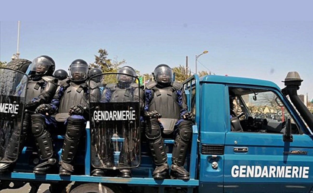 Image de Faits Divers. Dans la nuit du mardi 30 janvier 2024, une tragédie a frappé la gendarmerie nationale de Côte d'Ivoire. Le Maréchal des Logis-Chef Bahyo Ninsemon Jaurès, en service à la Brigade Territoriale d'Aniassué, a été mortellement abattu par un individu en tenue traditionnelle dozo, jetant l'ombre de la violence sur la paisible route de Satikran, dans le département d'Abengourou. Une Patrouille Mortelle Aux alentours de 23 heures, le MDL-Chef Jaurès et son binôme, l'Adjudant-Chef D.A.J.M., ont entrepris une patrouille aux abords du village de Satikran, près d'un point d'achat d'hévéa. Leur progression a été interrompue par un homme en tenue traditionnelle dozo, dont l'attitude énigmatique a précipité la tragédie. La Rencontre Fatale Alors que la patrouille approchait du village, l'inconnu en tenue dozo a perturbé les gendarmes en allumant brusquement sa torche, les éblouissant. Cherchant à identifier les gendarmes, le MDL-Chef Jaurès décline son identité, une action qui scelle tragiquement son destin. Sans avertissement, l'homme dozo ouvre le feu, abandonnant le gendarme grièvement blessé. Evacuation et Tragique Dénouement Transporté d'urgence au centre de santé rural de Satikran, le Maréchal des Logis-Chef, atteint à l'abdomen, lutte pour sa vie. Malheureusement, la gravité de ses blessures se révèle insurmontable, entraînant son décès. La nouvelle déchirante atteint rapidement ses collègues, mobilisant les autorités de la gendarmerie. Réaction des Autorité Le commandant de brigade et des éléments de la Brigade, alertés par l'Adjudant-Chef D.A.J.M., ainsi que les commandants de la septième légion de la Gendarmerie Territoriale et Mobile, convergent rapidement vers le lieu du drame, formant un détachement déterminé à faire la lumière sur cet acte odieux. Interpellations et Nécessité d'Enquête L'enquête, menée avec diligence, conduit à l'arrestation de deux individus lors d'une battue organisée. O. Karim, cultivateur ivoirien de Kodjina, et O. Seydou, conducteur de tricycle également domicilié à Kodjina, sont appréhendés. Parmi les autres individus interpellés dans le village figurent Y. K. Benjamin, propriétaire du pesage à Satikran, et K.A. Célestin, vigile du pesage également résidant à Satikran. Des Interpellations Multiples La battue initiée après le drame a conduit à plusieurs interpellations pour approfondir l'enquête. Outre les deux suspects majeurs, d'autres individus du village ont été appréhendés, parmi lesquels Y. K. Benjamin et K.A. Célestin, appelés à fournir des informations cruciales dans le but de comprendre les circonstances exactes de l'assassinat. L'assassinat du Maréchal des Logis-Chef Bahyo Ninsemon Jaurès a plongé la gendarmerie nationale dans le deuil et la consternation. Alors que les autorités s'efforcent de démêler les fils de cette tragédie, les questions demeurent sur les motivations de l'agresseur et les éventuelles failles dans la sécurité. En cette période sombre, la communauté gendarmique se recueille pour honorer la mémoire de l'homme qui a perdu la vie en protégeant la sécurité de tous.