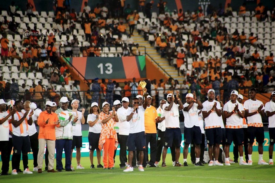 Deuxième Image de Société. Une soirée mémorable de célébration nationale a embrasé Abidjan le lundi 12 février 2024, alors que les Éléphants de Côte d'Ivoire, fraîchement couronnés champions de la 34e édition de la Coupe d'Afrique des Nations (CAN) de football, ont présenté avec éclat leur trophée au peuple ivoirien. La fièvre festive a culminé au stade Félix Houphouet-Boigny, plébiscité pour l'occasion, après une imposante parade à travers plusieurs communes de la capitale économique du pays. Un Triomphe Applaudi par les Plus Hautes Autorités La scène grandiose s'est déroulée dans un stade comble, résonnant des acclamations passionnées du public. Le Premier ministre ivoirien, Robert Beugré Mambé, les présidents d'institutions, ainsi que de nombreux membres du gouvernement, ont tous répondu présents, ajoutant une touche officielle à cette fête populaire. L'euphorie était palpable, chacun venant saluer la performance exceptionnelle des champions. Les Eléphants ont été les protagonistes incontestés de cette soirée inoubliable. Sous les projecteurs du "Felicia," le stade a vibré au rythme des ovations, applaudissant chaque joueur qui a contribué à cette victoire historique. Les rues d'Abidjan, empruntées par les champions africains, ont été le théâtre d'une parade mémorable, avec une marée humaine de supporters scandant des chants de gloire. Retour Triomphal dans les Rues d'Abidjan Avant la cérémonie au stade, les champions africains ont défilé dans les rues de la capitale économique, accompagnés par une foule en liesse. Le trophée tant convoité a été exhibé fièrement, symbolisant la réussite de la Côte d'Ivoire dans cette compétition acharnée. L'énergie positive dégagée par les supporters a transcendé la simple joie sportive pour devenir une expression collective de fierté nationale. La consécration des Éléphants à la 34e édition de la CAN a atteint son apogée lors de la finale épique qui s'est déroulée le dimanche 11 février 2024, au Stade Alassane Ouattara d'Ébimpé. Face au Nigéria, la Côte d'Ivoire a réalisé un exploit mémorable en remportant le match par un score de 2-1. Une performance qui restera gravée dans les mémoires, consacrant ainsi le statut d'icônes sportives des Éléphants. Hommage au Palais Présidentiel : Un Rendez-vous avec le Président Alassane Ouattara Le mardi 13 février 2024 restera également gravé dans l'histoire, alors que les Éléphants seront officiellement reçus au palais présidentiel d'Abidjan par le président Alassane Ouattara. Un moment d'honneur où la nation entière rendra hommage à ces ambassadeurs du football, mettant en lumière l'impact positif du sport sur l'unité nationale. La Côte d'Ivoire, déjà auréolée de la gloire de la CAN à trois reprises, peut désormais ajouter 2023 à sa liste prestigieuse de victoires. Les triomphes de 1992, 2015, et désormais 2023, soulignent la constance et la puissance du football ivoirien sur la scène continentale.* Alors que la nation célèbre cette victoire éclatante, une question demeure inévitable : Quel avenir attend les Éléphants de Côte d'Ivoire dans le paysage footballistique international? Avec une équipe qui a démontré sa force et son talent exceptionnels, comment la Côte d'Ivoire continuera-t-elle à marquer de son empreinte les compétitions à venir? Autant de réflexions qui guideront les attentes des fervents supporters et amateurs de football dans les mois à venir.