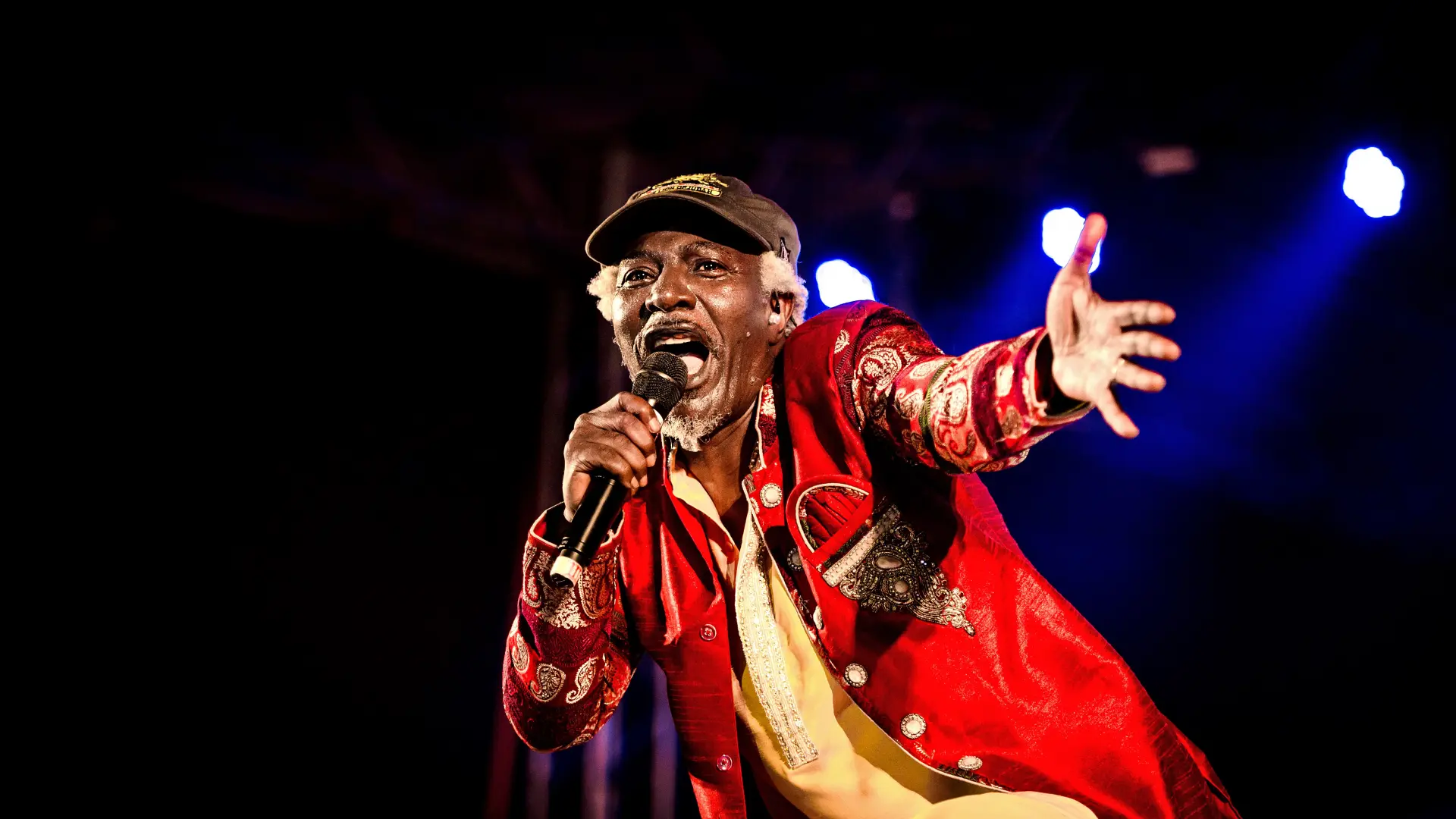 Image de Musique/Radio. Alpha Blondy, le "Rasta" ivoirien qui a secoué l'Afrique de l'Ouest dans les années 80, demeure une figure emblématique de la scène reggae. Né Seydou Koné le 1er janvier 1953 à Dimbrokro en Côte d'Ivoire, son parcours est jalonné de hauts et de bas, marqué par des moments sombres, mais aussi illuminé par des succès éclatants. Les Premiers Pas et les Frasques du Début des Années 80 Élevé par sa grand-mère Chérie Coco, Alpha Blondy, initialement Seydou Koné, a fait ses premiers pas dans le monde de la musique à la fin des années 70 à New York. C'est là qu'il découvre le reggae lors d'un concert des Jamaïcains de Burning Spear en 1977, un moment décisif qui le pousse à entamer sa carrière musicale. Après une période difficile, incluant un séjour dans un hôpital psychiatrique, Alpha Blondy se révèle au grand public en 1983 avec son premier album "Jah Glory". Le titre phare "Brigadier Sabari" raconte une opération coup-de-poing de la police ivoirienne, soulignant son engagement envers les réalités sociales de son pays. Les Années de Gloire : "Cocody Rock" et "Jerusalem" Le succès est instantané, et Alpha Blondy devient rapidement le "Marley" ivoirien. Installé à Paris en 1984, il signe avec la firme Pathé-Marconi (EMI) et enregistre l'album "Cocody Rock", incluant le titre éponyme enregistré à Kingston avec les célèbres Wailers. Il devient une véritable bête de scène, captivant la jeunesse africaine avec son énergie rebelle et son mélange de langues. En 1986, l'album "Jerusalem" est enregistré en Jamaïque avec une dimension œcuménique, mettant en avant la Tora après le Coran et la Bible. Alpha Blondy cherche à rassembler et réconcilier les hommes à travers sa musique. Engagement et Mysticisme : "Apartheid is Nazism" et "Masada" En 1987, Alpha Blondy sort "Apartheid is Nazism", un album militant à la liberté et à la paix, avec des titres comme "Jésus come back". Il révèle ainsi son aspect quasi mystique. En 1991, "Masada" voit le jour, marquant le retour d'Alpha Blondy sur la scène parisienne. Les chansons comme "Rendez-vous" font un carton, mais cette période est aussi marquée par des troubles émotionnels qui le conduisent à une tentative de suicide en 1993. Les Années 90 : Engagements Politiques et Nouveaux Horizons Malgré des problèmes de santé, Alpha Blondy revient en 1993 avec l'album "Dieu", explorant des thèmes polémistes et personnels. Les années suivantes sont marquées par sa présence sur la scène internationale, avec des tournées, des albums comme "Ytzah Rabin" en 1998, et une participation aux Grammy Awards en 2003. Nouveau Millénaire : Réconciliation, Engagement Social et Albums Majeurs Au début des années 2000, Alpha Blondy s'engage activement dans la vie politique de la Côte d'Ivoire, soutenant le président sortant Laurent Gbagbo. Il organise des concerts et des tournées, contribuant à l'effort de réconciliation nationale avec des initiatives telles que la "caravane de la réconciliation" aux côtés de Tiken Jah Fakoly.En 2007, après cinq ans de silence discographique, il revient avec "Jah Victory", un album qui reflète sa vision critique de la société. 2010 et au-delà : Positivité et Ouverture au Monde Les années 2010 voient la sortie de l'album "Vision" en 2011, suivi de "Positive Energy" en 2015. Ces albums témoignent de la maturité artistique d'Alpha Blondy, combinant le reggae avec des influences diverses et véhiculant un message positif. En 2022, Alpha Blondy présente "Eternity", un album qui continue d'explorer des thèmes sociaux et spirituels, montrant que sa voix résonne toujours sur la scène musicale mondiale. Alpha Blondy, l'enfant rebelle de la Côte d'Ivoire devenu la voix de la révolution musicale en Afrique, a laissé une empreinte indélébile sur le reggae mondial. Sa carrière tumultueuse, ses engagements sociaux et politiques, et sa musique transcendent les frontières, faisant de lui une figure emblématique de la scène musicale africaine et internationale. Alpha Blondy demeure une source d'inspiration pour les générations futures, prouvant que la musique peut être un puissant vecteur de changement et de réconciliation. Instagram Officiel : TikTok Officiel : Twitter Officiel :