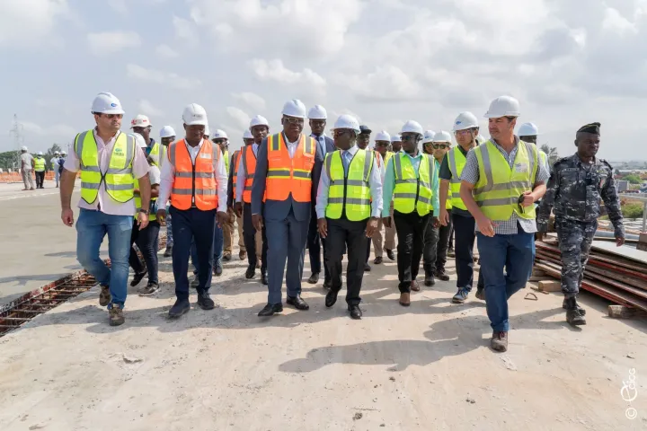 Image de Société. Les efforts déployés dans le cadre des travaux d'aménagement du carrefour Akwaba, amorcés en décembre 2021, commencent à porter leurs fruits. Le ministre de l'Équipement et de l'Entretien routier, Amédé Koffi Kouakou, a récemment annoncé que le projet était désormais réalisé à près de 65%. Cette déclaration survient à la suite d'une visite d'inspection sur le site, témoignant des progrès significatifs réalisés jusqu'à présent. Retard et Nouveaux Objectifs : Vers une Finalisation en Novembre 2024 Initialement prévue pour juin 2024, la conclusion des travaux a été repoussée à novembre de la même année en raison de diverses difficultés techniques rencontrées sur le chantier. Le ministre Kouakou a exprimé sa confiance quant à l'achèvement complet du projet d'ici le début du mois de décembre, tout en exhortant les entreprises impliquées à respecter les nouveaux délais. Le carrefour Akwaba, situé à Port-Bouët, constitue un point stratégique reliant plusieurs axes majeurs de la région, notamment le Boulevard Valéry Giscard d'Estaing, la Rue Atlantique Caraïbes, l'autoroute de Grand Bassam et la Voie Express de l'Aéroport d'Abidjan. Les travaux comprennent la construction d'un ouvrage principal, d'une chaussée à plusieurs voies, ainsi que la mise en place d'un carrefour giratoire et de raccordements aux axes principaux, avec des parois de soutènement renforcées. Des Attentes Élevées et une Surveillance Rapprochée Outre son importance en termes d'infrastructures, ce projet revêt une dimension sociale significative, créant des opportunités d'emploi pour environ 85% de jeunes Ivoiriens et contribuant ainsi à la lutte contre le chômage et au renforcement des compétences locales. Avec la nouvelle échéance fixée à novembre 2024, les attentes sont considérables quant à la transformation du carrefour Akwaba en un modèle d'aménagement urbain. Les autorités restent optimistes quant à la capacité des équipes à respecter les délais et à garantir la qualité des travaux. Elles s'engagent à surveiller de près l'évolution du chantier afin d'assurer une livraison dans les meilleures conditions. Quels Impacts le Carrefour Akwaba Aura-t-il sur la Mobilité Urbaine et l'Économie Locale ?