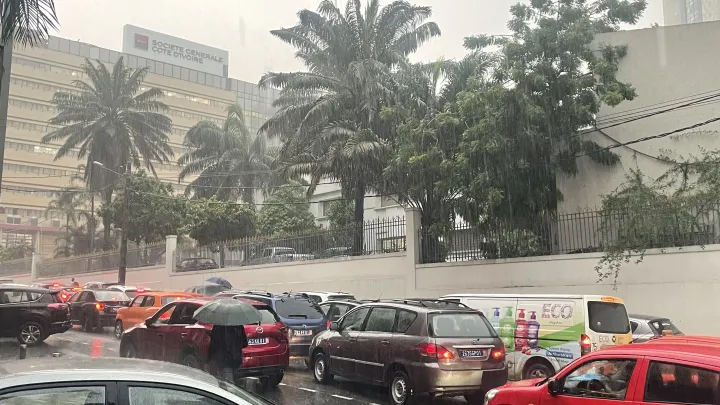 Image de Société. Le jeudi 13 juin 2024 restera marqué dans la mémoire des habitants d'Abidjan, touchés par des pluies diluviennes qui ont provoqué des inondations massives dans plusieurs quartiers. Cette situation météorologique extrême a mis à l'épreuve l'infrastructure de la ville, affectant la vie quotidienne de milliers de personnes et soulignant les défis urbains en matière de gestion des catastrophes naturelles. Chronique d'une journée sous l'eau Dès l'après-midi, le ciel d'Abidjan s'est assombri, donnant lieu à une pluie continue et abondante. Les quartiers de Cocody-Angré les Oscars, Riviera Palmeraie, et plusieurs secteurs de Yopougon, dont Niangon et Toit Rouge, se sont rapidement trouvés submergés. Les rues transformées en rivières ont entravé la circulation, générant des embouteillages monstres et paralysant l'activité économique. Police Secours a rapidement communiqué sur les zones affectées, exhortant les citoyens à la prudence. Des équipes de secours ont été déployées pour évaluer les dégâts et assister les résidents les plus touchés. Malgré ces efforts, la rapidité et la violence de l'évènement ont laissé peu de marge pour une intervention préventive efficace. La circulation a été sévèrement perturbée, avec des véhicules immobilisés et des routes inaccessibles. Cette situation a mis en lumière les déficiences structurelles de la ville en matière de drainage et de gestion des eaux pluviales. L'administration météorologique a émis des alertes pour les prochaines heures, prévoyant des orages et des averses continues sur une grande partie du territoire ivoirien. Les habitants sont appelés à une vigilance accrue, surtout ceux des régions du Littoral, du Sud-forestier, et du Nord-ouest, également menacés. Enjeux et Perspectives Ces inondations récurrentes posent avec acuité la question de l'aménagement urbain et de la nécessité d'investir dans des infrastructures capables de résister à ce type de phénomènes. La croissance rapide d'Abidjan et de ses environs a souvent été réalisée au détriment de la planification à long terme, notamment en matière de canalisations et de systèmes d'évacuation des eaux. Face à ces défis, la solidarité entre citoyens et les initiatives communautaires prennent une place prépondérante. Des histoires de voisins aidant voisins, de jeunes organisant des groupes de secours spontanés, démontrent la capacité de la communauté à s'organiser face à l'adversité. Les pluies torrentielles qui ont inondé Abidjan ce 13 juin ne sont pas seulement un rappel de la force de la nature, mais aussi un signal d'alarme pour les décideurs et les citoyens. Il est impératif de repenser la gestion urbaine pour faire face efficacement à ces événements et minimiser leurs impacts futurs. Alors que la ville se remet lentement de cette épreuve, les efforts doivent être redoublés pour garantir la sécurité et le bien-être de tous ses habitants. Comment Abidjan peut-elle se transformer pour mieux faire face aux défis climatiques croissants et garantir la sécurité de ses citoyens face à des phénomènes météorologiques de plus en plus extrêmes?