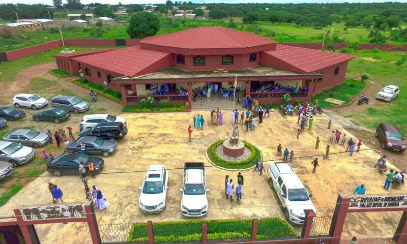 Image de Culture. À l'approche du quatrième centenaire du royaume Koulango, la région de Bouna se prépare à célébrer un événement d'envergure avec l'inauguration officielle du palais royal. Prévue du 25 au 27 juillet 2024, cette cérémonie marquera non seulement l'histoire de ce peuple, mais aussi un moment de fierté et de réaffirmation culturelle. La construction du palais, débutée en 2016 sous le règne du regretté roi Djarakoroni II, est une œuvre qui incarne la tradition et l'avenir du royaume. Un Édifice Chargé d'Histoire et de Signification Le palais royal de Bouna, conçu comme une rotonde comprenant six grandes salles, est un chef-d'œuvre architectural qui intègre des éléments esthétiques et fonctionnels traditionnels Koulango. Ce bâtiment ne se contente pas d'offrir des espaces pour les rencontres officielles et les décisions administratives, mais il abrite également un musée de civilisation et une bibliothèque riche en documents sur l'histoire et les traditions du peuple Koulango. Ces installations visent à préserver et à valoriser le patrimoine culturel du royaume. Initiée il y a près d'une décennie, la construction du palais a été marquée par une attention méticuleuse aux détails qui reflètent la grandeur de la culture Koulango. Les artisans locaux ont utilisé des techniques traditionnelles tout en intégrant des matériaux modernes pour garantir la durabilité de l'édifice, faisant du palais un symbole de la fusion entre le passé, le présent et l'avenir. Célébration du 400e Anniversaire : Une Affaire de Grandeur Les festivités du 400e anniversaire promettent d'être un spectacle grandiose, avec une série d'activités culturelles et traditionnelles. Des personnalités de marque, des dignitaires, des chefs traditionnels et des visiteurs de tout le pays et d'ailleurs sont attendus pour rendre hommage à l'histoire et à la résilience du peuple Koulango. L'événement sera également une occasion de renforcer les liens communautaires et de promouvoir le tourisme culturel dans la région. L'inauguration du palais royal est perçue par beaucoup comme une renaissance culturelle pour le peuple Koulango. Il est prévu que le palais devienne un lieu central pour les événements culturels, les décisions politiques et les cérémonies traditionnelles, renforçant ainsi son rôle de capitale culturelle et administrative du royaume. De plus, le musée et la bibliothèque joueront un rôle crucial dans l'éducation des jeunes générations, leur permettant de se connecter avec leur héritage de manière vivante et interactive. L'inauguration du palais royal de Bouna est un moment de convergence entre le passé glorieux et l'avenir prometteur du royaume Koulango. Alors que les préparatifs vont bon train pour accueillir cette célébration historique, l'enthousiasme et la fierté enveloppent la communauté. En regardant vers l'avenir, comment le palais royal de Bouna peut-il continuer à servir de pierre angulaire pour la préservation et l'épanouissement de la culture Koulango ?