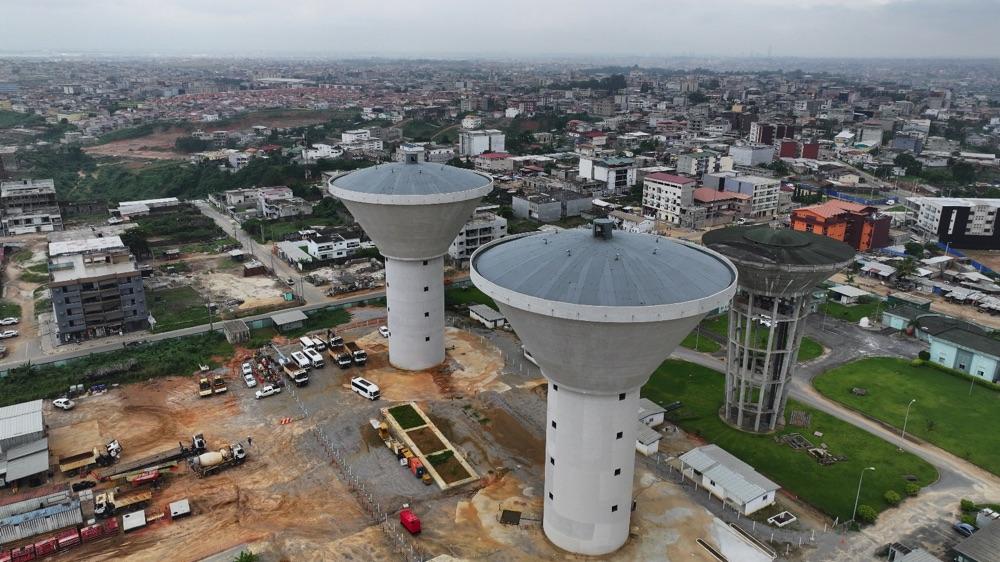 Image de Société. En Côte d'Ivoire, l'accès à l'eau potable est une priorité nationale. Le gouvernement ivoirien a entrepris des projets ambitieux pour garantir un approvisionnement constant et de qualité en eau potable à ses populations. Avec des investissements colossaux et la réalisation d'infrastructures majeures, le pays vise à transformer radicalement le paysage hydraulique urbain et rural d'ici 2030. Des Projets Structurants pour Abidjan et ses Environs Le gouvernement ivoirien a annoncé la construction d'une usine d'eau potable exploitant la lagune Aghien, la plus grande réserve d'eau douce du pays, située à l'est d'Abidjan. Cette usine, d'une capacité de production estimée à 150 000 m³/jour, représente un investissement de 22,3 milliards de FCFA. Le projet inclut la réalisation de 21,6 km de canalisations et la construction de trois lignes électriques de moyenne tension sur 17,5 km, assurant une distribution efficace de l'eau dans les communes de Cocody, Bingerville, Abobo, Yopougon et Plateau. L'inauguration de la station de traitement de la Mé à Kongofon en juin 2023 est une illustration claire de l'engagement continu du gouvernement à améliorer l'accès à l'eau potable. Avec une capacité de production de 240 000 m³/jour, cette station répond aux besoins croissants de la population abidjanaise et de ses environs, confirmant la détermination du pays à résoudre la question de l'accès à l'eau potable. À Abobo-Avocatier, un nouveau château d'eau d'une capacité de 5 000 m³/h a été construit pour soulager les populations locales. Ce projet, qui alimentera environ 50% de la population de la commune, représente une avancée significative dans l'amélioration des conditions de vie des habitants de cette zone densément peuplée. Des projets ont également été lancés dans les départements de Toumodi et d'Oumé, avec des investissements estimés à 100 milliards de FCFA. Ces initiatives visent à mettre fin aux pénuries d'eau dans le district autonome des Lacs, offrant ainsi une solution durable aux problèmes d'approvisionnement en eau potable. Dans plusieurs localités comme Koyékro, Yocoboué et Lataha, des progrès significatifs ont été réalisés. À Yocoboué, par exemple, la réhabilitation du système d'alimentation en eau potable en 2018 a mis fin à un calvaire de 34 ans pour les habitants. Dans la vallée du Bandama, le projet de renforcement de l'alimentation en eau potable de Bouaké et des localités environnantes a été essentiel pour pallier les effets de la sécheresse et améliorer l'accès à l'eau. Le Projet des 12 Villes Le projet des 12 villes, financé par Eximbank Chine, est une autre réalisation majeure visant à améliorer l'accès à l'eau potable. Avec un coût global de 170,250 milliards de FCFA, ce projet couvre des villes comme Bouaflé, Boundiali, Daloa, Divo, Grand-Lahou, Katiola, Mankono, Odienné, Sassandra, Séguéla, Touba et Tanda. Les travaux en cours promettent de transformer les infrastructures hydrauliques de ces régions, assurant une couverture en eau potable jusqu'en 2040. L'objectif du gouvernement ivoirien est clair : atteindre un taux d'accès à l'eau potable de 95% en 2025 et de 100% en 2030. Cet engagement s'inscrit dans le cadre de l'ambitieux programme vision 2030 du Président de la République pour une "Côte d'Ivoire solidaire". L'ensemble des projets de production, de transport et de fourniture d'eau dans le district d'Abidjan et dans les grandes villes de l'intérieur du pays visent à rendre l'accès à une source d'eau potable une réalité quotidienne pour tous. Les investissements et les réalisations en matière d'infrastructures hydrauliques en Côte d'Ivoire témoignent de l'engagement du gouvernement à améliorer les conditions de vie de ses citoyens. Alors que le pays progresse vers ses objectifs de 2025 et 2030, la continuité et l'efficacité de ces projets seront cruciales pour assurer un accès équitable et durable à l'eau potable. Comment la Côte d'Ivoire peut-elle continuer à innover et à financer durablement ses projets hydrauliques pour garantir un accès universel à l'eau potable tout en affrontant les défis climatiques et démographiques futurs?