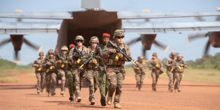 Image de Politique. La réduction de la présence militaire française en Afrique a récemment pris un tournant significatif en Côte d'Ivoire, où le 43e Bataillon d'Infanterie de Marine (43e BIMa), historiquement installé à Port-Bouët, se prépare à un retrait, marquant une étape importante dans le transfert de responsabilités aux Forces Armées de Côte d'Ivoire (FACI). Cette démarche s'inscrit dans un contexte de réajustement global des stratégies militaires françaises sur le continent africain, où les sentiments anti-français et les revendications d'autonomie s'intensifient. Contexte Historique et Stratégique Le 43e BIMa, une unité emblématique des troupes de marine françaises, tient ses racines du 43ᵉ Régiment d’Infanterie Coloniale. Stationné à Port-Bouët depuis le 1ᵉʳ juillet 1978 suite à un accord militaire franco-ivoirien, ce bataillon a traversé diverses phases, y compris une dissolution lors de l'opération Licorne, avant de renaître en 2016. Ce renouveau symbolisait non seulement un engagement continu envers la sécurité régionale mais aussi une adaptation aux nouvelles réalités géopolitiques. Au-delà du 43e BIMa, d'autres entités comme le Détachement Air 168 et diverses directions supportant les opérations logistiques et de défense témoignent de l'étendue de l'engagement français. Ces unités jouent des rôles cruciaux, allant du soutien logistique au renforcement des capacités des FACI, et contribuent ainsi à une présence sécuritaire et développementale durable. La dynamique de la présence militaire française en Afrique est également marquée par des pressions accrues dans le Sahel, notamment après les récents coups d'État militaires au Burkina Faso, au Mali et au Niger. Ces événements ont exacerbé le sentiment anti-français, culminant dans des demandes explicites de retrait des troupes françaises. Ces développements ont incité la France à reconsidérer ses stratégies, se concentrant sur la stabilisation plutôt que sur une présence expansive. La Transition à Port-Bouët La préparation pour le transfert de la base de Port-Bouët aux FACI est en cours, avec des modalités de rétrocession définies pour garantir une transition fluide. L'objectif est de rendre les FACI pleinement autonomes, capables de maintenir la sécurité et de répondre efficacement aux défis régionaux. Ce transfert symbolise une nouvelle ère de coopération militaire, où les capacités locales sont primordiales. Le retrait du 43e BIMa et le transfert de responsabilités aux FACI peuvent renforcer les relations franco-ivoiriennes, tout en ouvrant des voies pour une collaboration plus équilibrée et respectueuse de la souveraineté nationale. Cela pourrait également servir de modèle pour d'autres transitions similaires dans la région. Le retrait du 43e BIMa de Port-Bouët est plus qu'un simple changement de garde; il reflète une adaptation aux réalités contemporaines et un engagement envers une présence militaire plus ciblée et mutuellement bénéfique en Afrique. Alors que la France redéfinit son rôle sécuritaire sur le continent, la question demeure : comment les futures coopérations militaires pourront-elles équilibrer entre efficacité opérationnelle et respect de la souveraineté nationale dans un environnement aussi complexe et changeant?