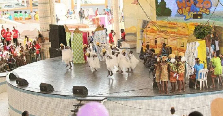 Image de Société. Pour la première fois dans l’histoire du Wozo Vacances, la grande finale de ce concours emblématique se tiendra en dehors des murs du Palais de la Culture de Treichville. En choisissant le Parc des Expositions de Port-Bouët, le comité d’organisation marque un tournant décisif pour cet événement qui, depuis des décennies, fait vibrer la jeunesse ivoirienne. Cette décision, motivée par une volonté d’accessibilité et de grandeur, suscite à la fois excitation et questionnements quant aux défis logistiques et émotionnels qu’elle implique. Un choix inédit : Port-Bouët, nouvel écrin de la finale L’annonce a fait l’effet d’une bombe. Pour l’édition 2024 du Wozo Vacances, la grande finale ne se déroulera pas, comme à l’accoutumée, dans le cadre mythique du Palais de la Culture de Treichville. Cette année, c’est le Parc des Expositions de Port-Bouët qui aura l’honneur d’accueillir ce rendez-vous tant attendu par les jeunes talents ivoiriens. Situé en périphérie d’Abidjan, ce site, qui peut accueillir jusqu’à 10 000 spectateurs, s’apprête à devenir le théâtre d’un spectacle mémorable. Le comité d’organisation, par la voix de son président, a justifié ce choix en évoquant avant tout la nécessité d’une plus grande accessibilité. "Nous souhaitions offrir à un maximum de jeunes Ivoiriens la possibilité de vivre cet événement unique. Le Parc des Expositions, avec sa capacité d’accueil, nous permet d’ouvrir davantage les portes de ce festival à un public plus large," a-t-il expliqué. En effet, si le Palais de la Culture reste un lieu symbolique, ses limites en termes de capacité ne permettaient pas de répondre à la demande croissante des spectateurs. Le déplacement de la finale vers le Parc des Expositions s’inscrit dans une stratégie plus large visant à redéfinir l’expérience Wozo Vacances. En choisissant un lieu d’envergure, les organisateurs entendent faire de cette édition 2024 un véritable spectacle à ciel ouvert, où grandeur et modernité se côtoient. Le Parc des Expositions, avec ses infrastructures modernes, offre un cadre idéal pour sublimer les performances des jeunes artistes en herbe. Par ailleurs, la délocalisation permet également d’envisager une augmentation significative des revenus issus de la billetterie. Avec une capacité d’accueil nettement supérieure, les recettes devraient suivre la même courbe ascendante, offrant ainsi de nouvelles perspectives pour le financement de futures éditions du Wozo Vacances. Cette manœuvre financière, bien que risquée, pourrait s’avérer payante si le public répond massivement présent. Les défis logistiques et organisationnels Cependant, ce changement de lieu n’est pas sans soulever des défis majeurs. Situé en périphérie d’Abidjan, le Parc des Expositions présente un problème de taille : son accessibilité. Si l’objectif est de permettre à un plus grand nombre de jeunes de participer, encore faut-il qu’ils puissent se rendre sur place. Le transport vers Port-Bouët, particulièrement pour les familles résidant dans le centre-ville ou les quartiers périphériques, pourrait s’avérer complexe et coûteux. Les organisateurs en sont conscients et ont d’ores et déjà entamé des discussions avec les autorités locales pour la mise en place de navettes gratuites ou à tarif réduit. "Nous travaillons activement avec les compagnies de transport pour faciliter l’accès au site. Des navettes seront déployées à partir des principaux points de rassemblement d’Abidjan pour acheminer les spectateurs jusqu’au Parc des Expositions," a annoncé le comité d’organisation. Au-delà de la logistique du transport, la question des coûts de location de l’arène demeure également un enjeu. Le Parc des Expositions, en raison de sa taille et de ses infrastructures, représente un investissement financier considérable. Pour rentabiliser cet investissement, les organisateurs pourraient être tentés de revoir à la hausse le prix des tickets d’entrée. Une décision qui, si elle permet de couvrir les frais, risque de rendre l’événement moins accessible pour certaines familles, contredisant ainsi l’objectif premier d’ouverture à un plus large public. L’impact émotionnel sur les jeunes participants Outre les défis logistiques, le changement de lieu pourrait également avoir un impact psychologique sur les jeunes finalistes. Habitués à la scène du Palais de la Culture, ces derniers devront s’adapter à un nouvel environnement, plus vaste et peut-être moins familier. Cette adaptation rapide pourrait générer du stress supplémentaire, voire de la nervosité, chez certains participants. "Les enfants sont très attachés aux repères, et un changement d’environnement, surtout dans le cadre d’une compétition aussi importante, peut déstabiliser," explique un psychologue spécialiste de l’enfance. "Ils devront non seulement gérer la pression de la compétition, mais aussi s’acclimater à un lieu totalement nouveau, ce qui n’est pas une mince affaire." Pour accompagner les jeunes artistes dans cette transition, le comité d’organisation a prévu des séances de préparation psychologique. Des professionnels seront mobilisés pour aider les finalistes à surmonter leur trac et à se familiariser avec la nouvelle scène. "Nous mettons tout en œuvre pour que les enfants se sentent à l’aise et puissent donner le meilleur d’eux-mêmes lors de cette finale," a rassuré le comité. Cette édition 2024 du Wozo Vacances s’annonce d’ores et déjà comme l’une des plus disputées. Cinq groupes se disputeront la première place lors de la grande finale : Nouvelle Vision de Danané, Les Petits Boyo Baya du Kabadougou, Les Enfants de la Nouvelle Vision de Bingerville, Koumala Système de Koumassi, et Yenouan Yekoun de M’Bahiakro. Chacun de ces groupes a su se distinguer au fil des sélections grâce à des performances remarquables, alliant talent, créativité et discipline. Le changement de lieu pourrait cependant ajouter une dose supplémentaire de tension à une compétition déjà intense. "La finale du Wozo Vacances est toujours un moment de grande émotion, mais cette année, avec le changement de décor, l’enjeu semble encore plus important," confie un membre du comité d’organisation. Les jeunes participants, conscients de l’importance de cette étape dans leur parcours, se préparent ardemment pour relever ce défi. "Nous sommes prêts à tout donner. Ce n’est pas parce que nous changeons de lieu que nous allons baisser les bras. Au contraire, nous allons montrer que nous sommes capables de nous adapter et de briller," déclare avec assurance un des finalistes. Le poids de l’héritage et l’importance de l’événement Wozo Vacances, au-delà d’un simple concours, est une institution en Côte d’Ivoire. Depuis sa création, cet événement a permis de révéler de nombreux talents, devenus aujourd’hui des figures emblématiques de la scène artistique ivoirienne. La finale, moment culminant du concours, est attendue chaque année avec impatience par les familles, les artistes en herbe et les passionnés de culture. Le déplacement de cet événement hors des murs du Palais de la Culture est donc perçu par certains comme une rupture avec la tradition, tandis que d’autres y voient une évolution nécessaire pour accompagner la croissance de l’événement. "Il est important de se renouveler et de s’adapter aux exigences du temps. Le Palais de la Culture a été un écrin parfait pour Wozo Vacances, mais aujourd’hui, nous devons penser plus grand," souligne un des anciens lauréats du concours. Cependant, cette transition ne doit pas faire oublier l’héritage culturel que représente Wozo Vacances. Cet événement a toujours été un symbole d’unité et de partage, un moment où la jeunesse ivoirienne se rassemble autour des valeurs de créativité, de discipline et de fraternité. Le Parc des Expositions, en accueillant cette finale, devra réussir à préserver cet esprit, tout en offrant une expérience nouvelle et enrichissante. Le choix du Parc des Expositions pour la finale de Wozo Vacances 2024 est donc un pari sur l’avenir. Il s’agit de repenser cet événement emblématique pour le rendre encore plus accessible, plus grandiose, et plus en phase avec les attentes des nouvelles générations. Si les défis sont nombreux, les opportunités le sont tout autant. Le comité d’organisation, conscient des enjeux, mise sur une préparation rigoureuse et une mobilisation sans précédent pour faire de cette finale un succès retentissant. Les retombées de cet événement pourraient bien dépasser le cadre strict de la compétition pour influencer durablement la culture et les pratiques événementielles en Côte d’Ivoire. Alors que Wozo Vacances s’apprête à entrer dans une nouvelle ère avec cette finale au Parc des Expositions, une question demeure : comment cet événement va-t-il évoluer dans un contexte ivoirien en pleine mutation ? La délocalisation de la finale marquera-t-elle le début d’une nouvelle dynamique pour le concours, ou bien ce changement sera-t-il perçu comme une rupture avec ses racines ? Face aux défis de la modernité et aux attentes croissantes des jeunes générations, Wozo Vacances saura-t-il rester fidèle à son esprit tout en s’adaptant aux exigences du temps ?