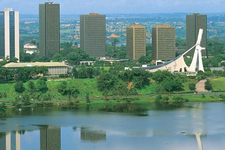 Image de Business/Investissement. L'urbanisation rapide du Grand Abidjan, véritable moteur économique de la Côte d'Ivoire, a provoqué une flambée des prix des terrains dans plusieurs communes, transformant ainsi le paysage immobilier de la métropole. Cette dynamique de croissance, tout en illustrant le développement économique, soulève également des questions cruciales sur l'accessibilité au logement et la durabilité du développement urbain dans l'une des villes les plus importantes d'Afrique de l'Ouest. Bingerville et Abatta : L'épicentre de la flambée des prix Bingerville, située à l'est d'Abidjan, se distingue comme l'une des communes où les prix des terrains ont atteint des sommets vertigineux. Le quartier d'Abatta, en particulier, niché au bord de la lagune Ebrié, est devenu l'un des endroits les plus recherchés. Avec des prix atteignant jusqu'à 100 000 FCFA le mètre carré, cette zone attire une clientèle aisée désireuse de s'installer dans un cadre résidentiel de haut standing, loin de l'agitation du centre-ville. Cette valorisation extrême des terrains à Abatta témoigne de l'attrait croissant pour les zones résidentielles haut de gamme en périphérie d'Abidjan. "Nous observons un intérêt grandissant pour les espaces qui offrent à la fois proximité avec la nature et accessibilité aux centres économiques," a expliqué un agent immobilier local. La demande pour des terrains dans ces quartiers exclusifs est alimentée par une classe moyenne en expansion et des expatriés en quête de tranquillité. À Grand-Bassam, ancienne capitale coloniale de la Côte d'Ivoire, les prix des terrains ne cessent également d'augmenter. Le quartier de France Extension, en particulier, voit le mètre carré se négocier à environ 60 000 FCFA. Cette hausse s'explique par la double valeur historique et résidentielle du lieu, classé au patrimoine mondial de l'UNESCO. "Grand-Bassam offre une combinaison unique de charme historique et de potentiel touristique," affirme un expert en patrimoine. Le potentiel touristique de Grand-Bassam, combiné à une demande croissante pour des résidences de luxe, alimente la hausse des prix. La proximité de la ville avec Abidjan et la qualité de vie qu'elle offre en font une destination privilégiée pour les investisseurs cherchant à diversifier leurs actifs immobiliers. Assinie, célèbre station balnéaire, complète ce podium des localités les plus prisées avec des terrains en bord de mer atteignant 50 000 FCFA le mètre carré. Réputée pour ses plages paradisiaques et ses complexes hôteliers de luxe, Assinie attire une clientèle locale et internationale à la recherche d'un cadre de vie exceptionnel. "Les terrains en bord de mer sont de plus en plus rares et donc très recherchés," souligne un promoteur immobilier. Cette valorisation reflète l'attrait persistant des destinations côtières pour les investisseurs et les particuliers fortunés, qui voient en Assinie non seulement une opportunité de résidence secondaire, mais aussi un investissement sûr et potentiellement lucratif. Jacqueville, Songon, et l'expansion de la zone urbaine d'Abidjan Les communes de Jacqueville et Songon, avec des prix avoisinant les 30 000 FCFA le mètre carré dans leurs quartiers les plus prisés, illustrent l'expansion continue de la zone urbaine d'Abidjan. L'amélioration des infrastructures, notamment avec la construction du pont Philippe-Yacé à Jacqueville, a facilité l'accès à ces communes, augmentant leur attractivité. "Ces nouvelles infrastructures ont transformé la dynamique de ces localités, les rendant plus accessibles et donc plus attractives pour les investisseurs," a déclaré un urbaniste. L'expansion urbaine vers ces communes témoigne de la volonté des autorités et des investisseurs de désengorger le centre-ville d'Abidjan tout en développant de nouvelles zones résidentielles. Cette tendance à la périphérisation pourrait cependant poser des défis en termes de gestion de l'étalement urbain et de préservation de l'environnement. À Anyama, les terrains les mieux situés atteignent désormais 25 000 FCFA le mètre carré, en grande partie grâce à l'impact des grands projets comme le Stade Olympique Alassane Ouattara. "Le développement d'infrastructures majeures attire des investissements et augmente la valeur des terrains environnants," a noté un économiste. Le développement rapide d'Anyama, autrefois perçue comme une banlieue éloignée d'Abidjan, montre comment les grands projets peuvent transformer le tissu urbain et redéfinir la carte immobilière. Cependant, cette croissance rapide pose aussi des questions sur la capacité des infrastructures locales à supporter une augmentation soudaine de la population et des activités économiques. Bonoua et Dabou, bien qu'étant en bas du classement des communes les plus chères, voient tout de même des prix culminant à 20 000 FCFA le mètre carré dans leurs quartiers les plus cotés. Ces localités, autrefois moins considérées par les investisseurs, bénéficient d'une amélioration des infrastructures et d'une demande accrue pour des terrains abordables. "L'intérêt pour Bonoua et Dabou reflète un désir de trouver des options plus économiques tout en restant proche d'Abidjan," explique un analyste immobilier. Cette tendance montre que même les zones périphériques peuvent devenir des points chauds du marché immobilier, en fonction de l'évolution des infrastructures et de la demande du marché. Si cette cartographie des prix des terrains dans le Grand Abidjan témoigne du dynamisme économique de la région, elle soulève également des inquiétudes quant à l'accessibilité au logement pour une grande partie de la population. La hausse des prix de l'immobilier dans les communes périphériques, souvent perçues comme des alternatives plus abordables, risque de rendre le logement de plus en plus inabordable pour les classes moyennes et populaires. Face à cette situation, les autorités sont confrontées à un défi de taille : comment concilier le développement urbain avec la nécessité de garantir un accès équitable au logement ? Des politiques d'aménagement du territoire plus inclusives et une régulation du marché immobilier pourraient être nécessaires pour éviter une gentrification excessive et préserver la mixité sociale qui fait la richesse d'Abidjan. Alors que le Grand Abidjan continue de croître à un rythme soutenu, la question demeure : comment la ville peut-elle équilibrer le développement immobilier avec l'accès équitable au logement et la préservation de l'environnement ? Les autorités locales et les acteurs du secteur immobilier sauront-ils élaborer des stratégies efficaces pour gérer cette croissance sans sacrifier la mixité sociale et la durabilité environnementale ?