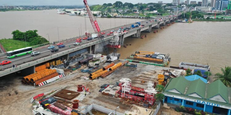 Image de Société. En Côte d'Ivoire, le ministère de l'Équipement et de l'Entretien routier a annoncé, ce jeudi 10 octobre 2024, la mise en place de travaux de resurfaçage sur le pont emblématique de Félix Houphouët-Boigny. Ces travaux, nécessaires pour garantir la sécurité des usagers et l'amélioration de la circulation, vont entraîner des perturbations importantes, notamment la fermeture totale du tablier ouest, reliant Treichville au Plateau, pendant huit jours. Une décision qui, bien qu'elle vise l'amélioration du réseau routier d'Abidjan, impacte considérablement la vie des Abidjanais et suscite une réflexion sur les infrastructures et la gestion de la mobilité dans la capitale économique ivoirienne. Travaux de resurfaçage : une nécessité pour la sécurité des usagers Le pont Félix Houphouët-Boigny, symbolique par son histoire et essentiel par sa fonction, relie deux quartiers stratégiques d'Abidjan : Treichville et le Plateau. Ce pont, qui voit transiter des milliers de véhicules chaque jour, est un axe vital pour la circulation et le développement économique de la ville. Avec le temps, le pont a commencé à présenter des signes d'usure, nécessitant des travaux d'entretien pour maintenir sa durabilité et garantir la sécurité des automobilistes et piétons. "Ces travaux de resurfaçage sont essentiels pour renforcer la structure du pont et éviter tout risque d'accident lié à la dégradation du tablier", a indiqué un responsable du ministère de l'Équipement et de l'Entretien routier. Le tablier ouest, qui relie Treichville au Plateau, sera donc fermé à partir de 22 heures ce soir jusqu'à 5 heures du matin le 18 octobre prochain. Pendant cette période, les équipes de maintenance vont travailler sans relâche pour rénover la chausée et renforcer la structure de l'ouvrage. Ces travaux interviennent dans le cadre d'un vaste programme de modernisation des infrastructures routières d'Abidjan, initié par les autorités pour améliorer la fluidité du trafic et la sécurité routière. L'objectif est de prévenir les risques et de prolonger la durée de vie des infrastructures existantes. "Il est primordial de maintenir les infrastructures en bon état pour accompagner le développement économique de la ville et assurer un cadre de vie sécurisé aux habitants", souligne un expert en infrastructures urbaines. Avec la fermeture du tablier ouest, la circulation sur le pont Houphouët-Boigny va inévitablement subir des perturbations importantes. Seul le tablier est restera accessible, mais avec une configuration en mode 2x1, réduisant ainsi de manière significative la capacité de passage. Cette réduction de la voie disponible pourrait entraîner une congestion accrue, notamment aux heures de pointe, lorsque les travailleurs se rendent dans les bureaux situés dans le quartier du Plateau, principal centre d'affaires d'Abidjan. Les autorités ivoiriennes recommandent aux usagers de prévoir des itinéraires alternatifs ou de privilégier les transports en commun et le covoiturage. "Nous encourageons fortement les automobilistes à adopter des pratiques de mobilité alternative durant cette période de travaux", a déclaré le ministre de l'Équipement et de l'Entretien routier. Cette recommandation s'inscrit dans une tentative de réduire la pression sur les axes routiers déjà très fréquentés. Les embouteillages sont depuis longtemps un problème majeur pour Abidjan, une ville en pleine expansion démographique et économique. La fermeture temporaire de l'une des principales voies de communication risque d'exacerber encore davantage cette situation. Des mesures de réorganisation du trafic ont été mises en place pour minimiser les dérives de circulation, mais les défis restent importants. "Le pont Houphouët-Boigny étant un point névralgique, nous nous attendons à des embouteillages significatifs, malgré nos efforts de coordination", prévient un fonctionnaire municipal. Un enjeu de modernisation pour les infrastructures routières d'Abidjan Les travaux de resurfaçage sur le pont Félix Houphouët-Boigny s'inscrivent dans un vaste programme de modernisation des infrastructures d'Abidjan, qui a pour objectif de rendre la circulation plus fluide et de renforcer la sécurité sur les routes. Depuis plusieurs années, la capitale économique de la Côte d'Ivoire fait face à une augmentation exponentielle du nombre de véhicules, sans que les infrastructures ne soient toujours adaptées à cette pression croissante. La modernisation et la rénovation des ponts et chaussées deviennent alors des priorités pour éviter une paralysie totale de la ville. Abidjan, avec ses nombreux quartiers et son activité économique intense, est un carrefour commercial et un poumon économique pour la sous-région. Les infrastructures doivent être capables de supporter une forte mobilité quotidienne et d'accompagner l'évolution de la ville vers une métropole moderne. Le pont Félix Houphouët-Boigny, en tant qu'élément essentiel de cette infrastructure, doit donc faire l'objet de toute l'attention nécessaire. Pour les autorités, ces travaux de modernisation sont également une manière de préparer la ville aux défis futurs. "La ville d'Abidjan ne peut se permettre de stagner. La modernisation de nos infrastructures est un préalable indispensable pour attirer des investissements et pour permettre une circulation optimale des biens et des personnes", indique un responsable au sein du ministère de l'Équipement. Si les travaux sont présentés comme une nécessité pour améliorer le cadre de vie des Abidjanais, ils suscitent aussi des réactions mitigées parmi les usagers. Certains comprennent l'importance de ces rénovations pour la sécurité de tous. "Je préfère subir des embouteillages pendant quelques jours, mais rouler sur un pont en bon état qui ne met pas ma vie en danger", explique Salimata, une conductrice qui emprunte régulièrement le pont pour se rendre à son travail. Cependant, d'autres expriment leur frustration face aux perturbations engendrées. "La circulation à Abidjan est déjà compliquée en temps normal, mais avec la fermeture d'une partie du pont, ça va devenir un vrai calvaire. Les autorités devraient prévoir de meilleures alternatives pour éviter que tout le monde ne se retrouve coincé dans les bouchons", râle Koffi, un chauffeur de taxi. Cette situation met en lumière la difficulté de mener des travaux d'envergure sur des infrastructures essentielles, sans impacter significativement la vie quotidienne des habitants. Les autorités doivent jongler entre l'urgence de la rénovation et la nécessité de garantir une circulation fluide dans une ville déjà sujette à de fortes pressions de mobilité. Des solutions alternatives pour une meilleure gestion du trafic ? Pour tenter de réduire l'impact des travaux sur la circulation, les autorités ont recommandé l'usage des transports en commun et du covoiturage. Cependant, ces solutions, bien que pertinentes, ne sont pas toujours à la portée de tous. Le réseau de transport en commun d'Abidjan, composé principalement de bus et de minibus, reste confronté à des limites liées à la fréquence, la capacité et l'état des infrastructures. "Le covoiturage est une bonne idée, mais il n'est pas encore très ancré dans nos habitudes à Abidjan", remarque Adama, un cadre qui travaille dans le quartier du Plateau. "Il faudrait plus de sensibilisation pour encourager cette pratique, surtout lors des périodes de travaux majeurs comme celui du pont Houphouët-Boigny." Cette situation pose la question de la préparation de la ville aux défis de la mobilité urbaine, notamment en ce qui concerne le développement de modes de transport alternatifs et l'amélioration du réseau existant. Certaines voies secondaires pourraient être utilisées pour désengorger le trafic pendant la période de fermeture partielle du pont. Toutefois, ces routes, souvent étroites et mal entretenues, risquent elles aussi de devenir rapidement saturées. "Il faudrait à terme développer davantage d'infrastructures pour relier efficacement les différents quartiers de la ville et réduire la dépendance aux grands axes comme le pont Houphouët-Boigny", estime un urbaniste d'Abidjan. La fermeture partielle du pont Félix Houphouët-Boigny pour travaux pose, plus largement, la question de la capacité d'Abidjan à anticiper les besoins d'une ville en pleine croissance. La capitale économique ivoirienne, qui attire chaque année des milliers de nouveaux habitants, doit relever des défis majeurs en matière d'infrastructures, de transport et de mobilité urbaine. Comment éviter que de telles opérations de maintenance ne paralysent la ville dans l'avenir ? Pour certains experts, la solution passe par une diversification des infrastructures de transport, notamment par la construction de nouveaux ponts et la modernisation du réseau ferroviaire. "Abidjan a besoin de plus de voies d'accès et de transport en commun efficaces pour soulager les principaux axes, surtout en période de travaux", déclare un spécialiste en planification urbaine. La création de nouvelles lignes de transport en commun, notamment des trams ou des bus à haut niveau de service, pourrait constituer une solution pour réduire la pression sur les infrastructures existantes. Le projet de modernisation du pont Félix Houphouët-Boigny, bien qu'il entraîne des contraintes temporaires pour les usagers, est aussi un rappel de l'importance de prévoir l'avenir en matière d'infrastructures urbaines. Alors que les travaux se poursuivent, la question reste posée : comment Abidjan peut-elle mieux se préparer aux besoins croissants de mobilité et assurer un développement équilibré, capable de répondre aux attentes de ses habitants et de soutenir son essor économique ?