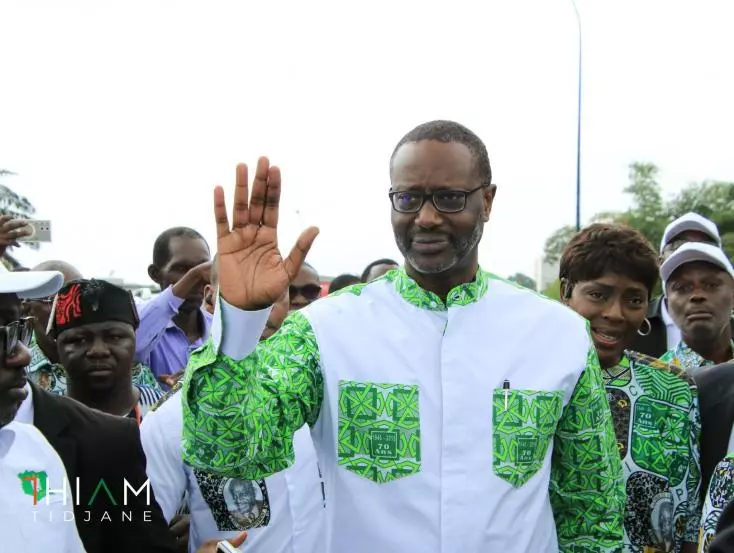 Deuxième Image de Politique. Né le 29 juillet 1962 à Abidjan, Tidjane Thiam est un dirigeant d'entreprise, homme politique et économiste d'origine ivoiro-française. Sa trajectoire exceptionnelle est marquée par des passages tant dans le secteur privé que dans le secteur public, en Afrique comme en Europe. Dirigeant d'envergure internationale, il s'est distingué par son engagement pour le développement économique de la Côte d'Ivoire, son rôle de pionnier au sein de grandes entreprises multinationales, et son influence grandissante sur la scène politique ivoirienne. Voici le récit d'une vie riche en événements, en innovations et en leadership. Jeunesse et influences familiales Tidjane Thiam naît au sein d'une famille à la croissée de deux mondes influents de l'Afrique de l'Ouest. Sa mère, originaire de Côte d'Ivoire, est liée à la famille du premier président de la République de Côte d'Ivoire, Félix Houphouët-Boigny, ce qui place dès son jeune âge Tidjane Thiam dans un environnement où politique et pouvoir se mêlent. Sa grand-mère maternelle, Aka Amoin Thérèse, était la cousine d'Houphouët-Boigny, établissant ainsi un lien direct avec l'une des figures les plus emblématiques de la politique ivoirienne. Son père, Amadou Thiam, d'origine sénégalaise, est un journaliste chevronné et un homme politique influent. Diplômé de l'Institut international de journalisme de Strasbourg, il quitte le Sénégal en 1947 pour s'installer en Côte d'Ivoire. Soutien actif d'Houphouët-Boigny durant la lutte pour l'indépendance, Amadou Thiam joue un rôle clé dans la sphère médiatique ivoirienne, devenant directeur de Radio Côte d'Ivoire en 1959, puis occupant par la suite deux fois le poste de ministre de l'Information. Parallèlement, la figure de son oncle Habib Thiam, qui fut Premier ministre du Sénégal et président de l'Assemblée nationale de ce pays, enrichit l'héritage politique dans lequel Tidjane Thiam grandit. Benjamin d'une fratrie de sept enfants, Tidjane est entouré de personnalités aux parcours tout aussi impressionnants. Chacun de ses frères et sœurs a su tracer sa propre voie, allant de la politique ivoirienne à la scène internationale, en passant par l'économie et la médecine. Cette famille soudée et influente lui inculque un sens profond de la responsabilité sociale et du dévouement au service de la collectivité. Les études : Un parcours de l'excellence Après avoir suivi ses études secondaires au lycée classique d'Abidjan, Tidjane Thiam quitte la Côte d'Ivoire en 1980 pour poursuivre ses classes préparatoires au lycée privé Sainte-Geneviève, à Versailles. Là, il se distingue par ses excellents résultats et parvient à intégrer l'École polytechnique en 1982, devenant le premier Ivoirien à y être admis. Ce succès reflète non seulement ses capacités académiques, mais aussi sa détermination à surmonter les barrières culturelles et géographiques. En 1986, après avoir brillamment achevé son cursus à l'École des Mines de Paris, dont il sort major de promotion, Tidjane se voit offrir une bourse pour suivre un MBA à l'INSEAD. Il intègre également le programme de formation des jeunes cadres à McKinsey & Company, où il travaille en tant que consultant en management. En 1989, Tidjane Thiam prend une année sabbatique pour participer au Programme des jeunes professionnels de la Banque mondiale à Washington, D.C. Il retourne ensuite chez McKinsey, cette fois-ci à Paris, consolidant ainsi ses compétences dans le conseil aux entreprises. Ces années de formation représentent bien plus qu'un simple parcours universitaire. Elles incarnent pour Tidjane Thiam un apprentissage en profondeur des dynamiques économiques et des enjeux internationaux, qui vont par la suite guider sa carrière à travers le monde. Le retour en Côte d'Ivoire : Au service de l'État En 1994, à seulement 31 ans, Tidjane Thiam se voit offrir l'opportunité de retourner en Côte d'Ivoire pour occuper le poste de directeur général de la Direction et Contrôle des Grands Travaux (DCGT). Sous la présidence d'Henri Konan Bédié, cet organisme se transforme en Bureau National d'Études Techniques et de Développement (BNETD), une structure étatique chargée de la planification des grands projets d'infrastructures et du conseil économique. Cette nomination représente une étape importante pour Thiam, marquée par un retour aux sources et une volonté manifeste de contribuer au développement de son pays d'origine. Le début de cette mission coïncide avec la dévaluation de 50 % du franc CFA, qui plonge la région dans une crise économique sans précédent. Tidjane Thiam se retrouve alors à négocier avec le FMI et la Banque mondiale, deux acteurs incontournables pour stabiliser la situation financière du pays. Sa compétence et sa maîtrise des rouages économiques lui valent une reconnaissance rapide. En 1998, il devient non seulement président du BNETD, mais aussi ministre du Plan et du Développement. Cette double casquette lui permet de méner à bien plusieurs grands projets de modernisation, parmi lesquels la construction du pont à péage de la Riviera-Marcory, la centrale électrique d'Azito, et la rénovation de l'aéroport d'Abidjan. Les réformes entreprises par Tidjane Thiam ne se limitent pas aux infrastructures. Il participe activement au programme de privatisation des principaux secteurs stratégiques du pays, une mesure exigée par les bailleurs de fonds internationaux. De nombreux services publics sont ainsi délégués au secteur privé, du téléphone à la production d'électricité, en passant par les aéroports et le réseau ferroviaire. Ces choix polémiques suscitent des critiques, mais permettent au pays de s'engager sur la voie des réformes économiques et d'attirer des investisseurs. Coup d'État et retour en exil La trajectoire de Tidjane Thiam en tant que ministre s'interrompt brutalement en 1999, à la suite d'un coup d'État militaire mené par le général Robert Guéï. Alors qu'il est en déplacement à l'étranger, le gouvernement est renversé, marquant le premier coup d'État dans l'histoire de la Côte d'Ivoire indépendante. De retour au pays, Tidjane Thiam est assigné à résidence par les nouvelles autorités militaires, puis libéré après quelques semaines. Le général Guéï lui propose un poste dans le nouveau gouvernement, mais Tidjane refuse, préférant quitter le pays pour retourner en Europe. Ce second exil constitue pour lui un moment charnière, marqué par une introspection et une réorientation vers le secteur privé. Tidjane Thiam s'engage alors dans un parcours remarquable au sein de l'industrie financière, s'imposant peu à peu comme une figure incontournable des affaires internationales. De retour à Paris en 2000, Tidjane Thiam retrouve ses fonctions chez McKinsey & Company, où il est nommé associé, devenant ainsi un acteur influent au sein du département des institutions financières de la firme. En 2002, il rejoint Aviva, l'un des plus grands assureurs au monde, et y occupe plusieurs postes stratégiques, notamment celui de directeur de la stratégie et du développement du groupe. En 2007, Tidjane Thiam quitte Aviva pour devenir directeur financier chez Prudential, un groupe d'assurances britannique de premier plan. En 2009, il est promu directeur général de Prudential, devenant ainsi le premier dirigeant noir d'une entreprise du FTSE 100, l'indice des plus grandes entreprises cotées à la Bourse de Londres. C'est un moment historique qui marque non seulement une percée personnelle, mais aussi une avancée importante dans la diversité du leadership au sein des entreprises mondiales. Sous sa direction, Prudential lance une offre de rachat de la branche asiatique de l'assureur américain AIG, pour un montant de 35,5 milliards de dollars. Bien que l'opération finisse par échouer, cet épisode témoigne de l'audace de Tidjane Thiam et de sa vision stratégique. L'échec du rachat est critiqué, mais la performance globale de Prudential sous sa direction demeure solide, et il est réélu avec une large majorité lors de l'assemblée générale des actionnaires en 2011. En 2015, Tidjane Thiam rejoint le Crédit Suisse en tant que directeur général. Il entreprend une restructuration ambitieuse de la banque, réorientant ses activités vers la gestion de fortune et réduisant les risques liés aux activités de banque d'investissement. Sous sa houlette, Crédit Suisse renoue avec la rentabilité après une période de difficultés. Cependant, des polémiques éclatent, notamment en 2019, lorsque l'un de ses bras droits est accusé d'avoir fait surveiller un ancien cadre dirigeant. Bien que Tidjane Thiam soit blanché de toute implication directe, cet incident ternit son image au sein de l'établissement. En février 2020, Tidjane Thiam démissionne de ses fonctions au Crédit Suisse. Cette décision est perçue par beaucoup comme la conséquence d'une accumulation de tensions au sein de la direction et d'une pression accrue de l'establishment bancaire suisse. Certains analystes évoquent même le racisme ambiant des milieux d'affaires zurichois, une théorie relayée par le New York Times, qui revient sur les difficultés rencontrées par Thiam, notamment lors de sa participation à des événements où il était le seul dirigeant noir. Retour sur la scène internationale et implication en Afrique Après son départ du Crédit Suisse, Tidjane Thiam ne reste pas inactif. En novembre 2020, il est nommé président du conseil d'administration de Rwanda Finance Limited, une agence gouvernementale chargée de développer le Kigali International Financial Centre, une plateforme visant à renforcer le positionnement du Rwanda comme hub financier international. Tidjane Thiam continue également à s'investir dans des organisations internationales. Il est membre de l'Africa Progress Panel, un groupe dirigé par Kofi Annan et consacré à la promotion du développement en Afrique. Il est aussi engagé dans des initiatives relatives aux infrastructures, ayant été président du groupe d'experts du G20 sur les investissements dans les infrastructures, avec pour mission de favoriser l'implication du secteur privé dans les projets de développement des économies émergentes. En 2023, Tidjane Thiam retourne en Côte d'Ivoire et prend la tête du Parti démocratique de Côte d'Ivoire (PDCI), principal parti d'opposition, après avoir été élu avec une large majorité. Son retour est vu comme un signal fort de son engagement politique en faveur de la Côte d'Ivoire et du rôle qu'il entend jouer pour l'avenir de son pays. Un leader au carrefour des cultures et des continents Tidjane Thiam incarne un leadership singulier, situé au carrefour des cultures et des continents. Sa carrière à la fois politique et économique témoigne d'une capacité exceptionnelle à naviguer entre des sphères très différentes, tout en conservant une vision cohérente et ambitieuse. Son parcours est aussi marqué par des épreuves, qu'il a su surmonter grâce à une résilience et une détermination hors du commun. En tant que premier dirigeant noir d'une entreprise du FTSE 100, Tidjane Thiam a ouvert la voie à une plus grande diversité dans les instances dirigeantes des grandes entreprises. Il a été reconnu par l'INSEAD et par de nombreux observateurs comme un leader d'exception, capable d'inspirer non seulement par ses compétences techniques, mais aussi par sa volonté de construire des ponts entre l'Afrique et le reste du monde. En tant que président du PDCI, il a l'opportunité de mettre à profit son expérience internationale au service de son pays natal, avec l'espoir de contribuer à une transition politique pacifique et au développement économique de la Côte d'Ivoire. Sa volonté de combiner action publique et privée, avec un accent sur le développement des infrastructures et la modernisation économique, reflète sa vision d'une Afrique intégrée et prospère. Le parcours de Tidjane Thiam est celui d'un homme qui a su marquer son époque, tant par ses accomplissements personnels que par ses contributions au bien commun. Son histoire est celle d'un Africain qui, tout en étant ouvert sur le monde, reste attaché à ses racines et engagé envers son pays. En tant que dirigeant d'entreprise, ministre, et aujourd'hui leader politique, il continue d'influencer les débats sur l'avenir de la Côte d'Ivoire et de l'Afrique. Ses défis futurs ne sont pas moindres : le contexte politique ivoirien reste tendu, et la tâche de réconcilier un pays marqué par des décennies de tensions politiques ne sera pas aisée. Mais Tidjane Thiam semble prêt à relever ce défi, fort de son expérience unique et de son ambition pour une Côte d'Ivoire stable, moderne et prospère.