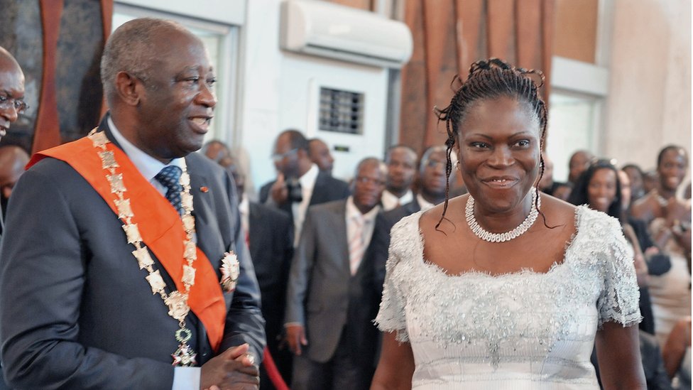 Troisième Image de Politique. Simone Ehivet Gbagbo, surnommée "la Dame de fer" en Côte d'Ivoire, est une figure politique incontournable et controversée, connue pour son courage, sa vision et sa persévérance. Ayant été Première Dame de Côte d'Ivoire pendant la présidence de Laurent Gbagbo, elle a non seulement marqué l’histoire par son influence politique, mais également par ses positions fermes et souvent tranchées sur des sujets clés, tant sur le plan national qu’international. À travers son parcours, Simone Gbagbo a inspiré des générations de femmes et d’hommes en Côte d'Ivoire, tout en suscitant débats et controverses. Sa biographie est celle d’une militante qui a surmonté de nombreux obstacles pour défendre ses convictions. Les premières années et les origines Simone Ehivet Gbagbo est née le 20 juin 1949 à Moossou, un village proche de Grand-Bassam en Côte d'Ivoire. Elle grandit dans une famille modeste et catholique, où elle est inculquée dès son jeune âge des valeurs de discipline, de travail et de persévérance. Son enfance est marquée par le respect des traditions et des valeurs chrétiennes, un héritage spirituel qui influencera plus tard son parcours politique et personnel. Très tôt, Simone Ehivet démontre une aptitude pour les études et un sens aigu de l’engagement communautaire. Elle est connue pour sa vivacité d'esprit et sa capacité à défendre ses idées, même à une époque où les femmes étaient rarement encouragées à exprimer leur opinion dans la sphère publique. Cette détermination à se faire entendre et à défendre des idées de justice et de progrès social est une caractéristique qui marquera toute sa carrière. Études et éveil politique Simone Ehivet poursuit ses études secondaires avec brio, avant de s’inscrire à l’Université d’Abidjan, où elle suit un cursus en linguistique. C'est là qu'elle obtient un doctorat, spécialisé dans la littérature orale, un domaine qui l’intéresse particulièrement. Passionnée par l’histoire et la culture de son pays, elle consacre son mémoire de recherche aux récits et traditions orales de la Côte d'Ivoire, cherchant à comprendre et à documenter le patrimoine culturel ivoirien. C'est également pendant ses années universitaires que Simone Gbagbo prend conscience des injustices sociales et des inégalités politiques qui sévissent dans le pays. Nous sommes alors dans les années 1970, et la Côte d'Ivoire, comme de nombreux autres pays africains, vit sous un régime autoritaire. Ces années d’études vont jouer un rôle déterminant dans son engagement pour le changement, la démocratie et la liberté. Elle commence à participer à des mouvements de contestation et se forge une réputation de militante tenace et engagée. Rencontre avec Laurent Gbagbo et la fondation du FPI C’est à l'université qu’elle rencontre Laurent Gbagbo, un intellectuel et militant politique avec qui elle partage une vision commune de justice sociale et de changement politique pour la Côte d'Ivoire. Ensemble, ils fondent en 1982 le Front Populaire Ivoirien (FPI), un parti politique d’opposition visant à instaurer le multipartisme dans un pays dominé par le parti unique de Félix Houphouët-Boigny. Cette rencontre marque le début d'un partenariat politique et personnel qui va profondément transformer la vie de Simone Gbagbo. Le FPI est d’abord une organisation clandestine, car toute opposition politique est réprimée sévèrement par le régime en place. Toutefois, Simone et Laurent Gbagbo sont déterminés à briser le monopole du pouvoir et à promouvoir la liberté d’expression et les droits politiques. Le FPI prône des idéaux socialistes et prône un changement radical de gouvernance pour le pays, qui est alors miné par le népotisme et la corruption. Les premières épreuves et l’emprisonnement Durant les années 1980, Simone Gbagbo, tout comme son mari, subit plusieurs arrestations. Elle est emprisonnée à plusieurs reprises pour ses activités politiques. Ces années de lutte et de répression forgent sa réputation de "Dame de fer" et renforcent son engagement pour la cause de la démocratie en Côte d'Ivoire. Elle se bat non seulement pour elle-même, mais également pour toutes les voix opprimées du pays. Son expérience en prison lui donne une perspective unique sur la résilience et le courage nécessaires pour survivre dans un environnement politique hostile. La montée en puissance : Simone Gbagbo, la députée Avec l’instauration du multipartisme en 1990, Simone Gbagbo est élue députée, marquant ainsi un tournant dans sa carrière politique. Elle représente la commune d'Abobo, un quartier populaire d’Abidjan, et devient l’une des premières femmes politiques influentes du pays. Son élection est perçue comme une victoire pour la démocratie et pour toutes les femmes ivoiriennes qui aspirent à jouer un rôle actif dans la société. En tant que députée, Simone Gbagbo continue de militer pour les droits des citoyens et pour une meilleure gouvernance. Elle est une critique sévère du gouvernement en place et n’hésite pas à dénoncer les abus de pouvoir et la corruption. Son style de communication direct et parfois intransigeant renforce son image de "Dame de fer". Elle s’impose alors comme l’une des voix les plus influentes et les plus redoutées du pays. Première Dame de Côte d'Ivoire (2000-2011) En 2000, Laurent Gbagbo remporte les élections présidentielles, devenant le chef de l'État ivoirien. Simone Gbagbo devient alors Première Dame, un rôle qu'elle remplit avec une forte implication politique. Contrairement à beaucoup de Premières Dames qui adoptent un rôle plus en retrait, Simone Gbagbo choisit d’influencer activement les décisions politiques. Elle est considérée comme l’un des conseillers les plus proches et les plus influents de Laurent Gbagbo. Sa proximité avec le pouvoir lui vaut à la fois des admirateurs et des détracteurs. Elle continue de jouer un rôle clé au sein du FPI et dans le gouvernement, se concentrant notamment sur les questions sociales et éducatives. Elle défend la cause des femmes et milite pour l'émancipation des jeunes. En parallèle, elle s’implique dans des activités religieuses et se rapproche du christianisme évangélique, influençant ainsi la politique sociale du gouvernement. La crise post-électorale de 2010-2011 En 2010, la Côte d'Ivoire plonge dans une crise post-électorale après l’élection présidentielle contestée. Laurent Gbagbo refuse de reconnaître la victoire d'Alassane Ouattara, le candidat déclaré vainqueur par la Commission électorale indépendante, ce qui entraîne une division et des violences à l’échelle nationale. Simone Gbagbo est accusée d’avoir joué un rôle clé dans la mobilisation des partisans du FPI pour résister à cette transition. Pendant la crise, des violences éclatent et des centaines de personnes perdent la vie. En avril 2011, après l’intervention des forces françaises et onusiennes, Laurent Gbagbo et Simone Gbagbo sont arrêtés dans leur résidence. Simone est inculpée pour atteinte à la sûreté de l’État et pour divers crimes commis pendant la crise. Elle est emprisonnée et, en 2015, est condamnée à 20 ans de prison, une sentence qui suscite des débats et des divisions au sein de la société ivoirienne. Années d'emprisonnement et libération Les années de détention de Simone Gbagbo sont marquées par des moments de solitude et de réflexion. Durant son incarcération, elle conserve un soutien important parmi ses partisans et continue de faire parler d'elle par ses interventions publiques. Elle exprime son souhait de voir la Côte d'Ivoire sur le chemin de la réconciliation nationale et s’efforce de maintenir ses convictions intactes, malgré les épreuves qu’elle traverse. En 2018, le président Alassane Ouattara décide de lui accorder une amnistie, ce qui conduit à sa libération après sept années d’emprisonnement. Cette amnistie est perçue comme un geste de réconciliation nationale, même si elle reste controversée pour certains. Retour en politique et fondation du Mouvement des Générations Capables (MGC) Après sa libération, Simone Gbagbo relance sa carrière politique en fondant le Mouvement des Générations Capables (MGC) en 2021. Ce nouveau mouvement politique marque une rupture avec le Front Populaire Ivoirien et représente une volonté de Simone Gbagbo de se repositionner de manière indépendante. Le MGC prône la réconciliation nationale, la justice sociale et l’émancipation de la jeunesse, dans un esprit de reconstruction pour la Côte d'Ivoire. Elle se consacre également à sensibiliser les femmes pour qu'elles s'engagent davantage en politique, affirmant que le leadership féminin est essentiel pour le développement du pays. Vie personnelle et héritage Simone Gbagbo et Laurent Gbagbo ont eu plusieurs enfants et ont traversé ensemble des années de luttes, d’incarcérations et de défis politiques. En tant que Première Dame et femme politique influente, elle a non seulement marqué l’histoire de la Côte d'Ivoire, mais aussi celle des femmes africaines engagées en politique. Ses années d'engagement, de souffrance et de résilience lui ont valu un respect indéniable, même parmi ses adversaires. Elle reste aujourd'hui une figure complexe : pour certains, elle est une héroïne de la démocratie, pour d'autres, une figure controversée en raison des événements tragiques de la crise post-électorale. Néanmoins, elle est indéniablement un modèle de ténacité et de détermination, qui continue d'influencer la politique ivoirienne par son engagement. Simone Gbagbo demeure l'une des figures politiques les plus influentes de la Côte d'Ivoire moderne. Sa vie et son parcours politique reflètent les luttes et les transformations de la société ivoirienne. En tant que femme engagée, elle a défendu des causes politiques avec passion et courage, marquant son époque et inspirant des générations de femmes en Afrique. Que l’on soutienne ou non ses idées, elle reste un symbole de résilience et de conviction, et une actrice incontournable de l’histoire politique ivoirienne. Instagram : X :