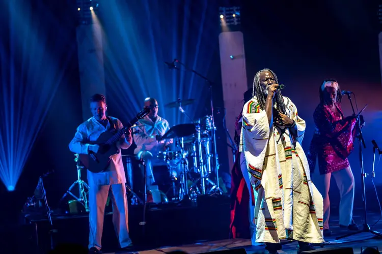 Image de Musique/Radio. Le 21 novembre 2024, le Théâtre de Champagne à Troyes a vibré au rythme du reggae, accueillant une prestation d’exception de Tiken Jah Fakoly. L’artiste ivoirien, figure emblématique du reggae africain, a marqué l’histoire en devenant le premier Ivoirien à participer au « Grand Choral », un événement majeur du festival Nuits de Champagne. Accompagné de 850 choristes, Tiken Jah a interprété sa célèbre chanson « Plus rien ne m’étonne », transformant cet instant en un véritable acte de résistance et de communion musicale. L'événement a mis en lumière la portée universelle du reggae, tout en soulignant l'importance de la voix collective et de l'engagement social à travers la musique. Retour sur une performance inoubliable qui a réuni des spectateurs de tous horizons autour des valeurs de paix, de tolérance et de liberté. Le Grand Choral : une institution musicale unique Le Grand Choral, pilier du festival Nuits de Champagne, est un événement incontournable qui réunit chaque année des choristes amateurs issus de toute la région. Créé en 1988, ce festival a fait de la voix un art à part entière, célébrant non seulement la musique, mais aussi le pouvoir de l’expression vocale collective. Depuis 1993, l’événement a pris une nouvelle dimension en fusionnant avec l’association Chanson Contemporaine, une structure dédiée à la promotion des auteurs-compositeurs. Ce mariage a permis au festival d'intégrer des créations collectives, où le public devient acteur d'une œuvre musicale vivante et en constante évolution. Au cœur de ce festival se trouve le Grand Choral, une performance exceptionnelle où près de 850 choristes amateurs se rassemblent pour chanter les œuvres d’un artiste invité, souvent une figure incontournable de la scène musicale internationale. Le chef d’orchestre, dans ce cas Brice Baillon, orchestre cette masse sonore en créant une harmonie parfaite entre les voix, tout en respectant la vision artistique de l’artiste invité. Cette année, c'est Tiken Jah Fakoly qui a eu l’honneur de figurer au programme, et son choix a ajouté une dimension particulière à cet événement. Tiken Jah Fakoly, connu pour son engagement politique et social à travers ses chansons, est l’un des artistes les plus influents du reggae africain. Depuis ses débuts dans les années 1990, il a su allier la puissance de ses paroles à l’énergie du reggae, en dénonçant les injustices sociales, les dérives politiques et les inégalités qui marquent l'Afrique et au-delà. Son œuvre est une véritable critique de la réalité socio-politique, mais elle est aussi un appel à la solidarité, à la tolérance et à la paix. L’interprétation de Tiken Jah au Grand Choral a été bien plus qu’une simple performance musicale. C’était un acte symbolique. En devenant le premier Ivoirien à participer à cet événement prestigieux, il a non seulement renforcé son statut d’artiste engagé, mais aussi mis en lumière la portée universelle de son message. Dans un monde où la musique est souvent utilisée comme un outil de distraction, Tiken Jah a choisi de l’employer comme un vecteur de réflexion et de résistance. Le moment fort de la soirée fut, sans conteste, l’interprétation de « Plus rien ne m’étonne », un hymne qui dénonce les dérives politiques et sociales en Afrique, mais qui résonne également à un niveau global. Cette chanson, véritable cri de ralliement pour les populations oppressées, a pris une nouvelle dimension lorsqu'elle a été chantée par 850 choristes amateurs, accompagnant l’artiste dans une explosion de son et de solidarité. Sous la direction de Brice Baillon, la performance a transcendé le simple cadre d'un concert. Le travail de l’orchestre vocal a permis de magnifier le message de Tiken Jah, tout en donnant à chaque choriste la possibilité de porter cette cause. Le mélange des voix, l’énergie palpable sur scène et la force des paroles ont créé une atmosphère unique, où chaque spectateur, qu’il soit musicien ou non, a pu ressentir la puissance du message porté par cette chanson. Les 850 choristes, venant de différents horizons, ont été les témoins et les acteurs d’une expérience musicale rare. Il ne s’agissait pas seulement de chanter, mais de s’unir pour exprimer une vérité commune. L’impact émotionnel de la prestation, tant sur scène qu’auprès du public, a été immédiat. En cette soirée de novembre 2024, le reggae est devenu une langue universelle, celle qui réunit et qui dépasse les frontières. Un message d’espoir et de résistance En choisissant de participer au Grand Choral, Tiken Jah Fakoly a fait un geste fort. Ce choix n’était pas simplement lié à sa carrière musicale, mais également à sa volonté de porter un message de paix et de résistance. À travers des paroles engagées et poignantes, l’artiste a rappelé l’importance de la liberté et de la tolérance, valeurs essentielles qui devraient guider les sociétés modernes. "Plus rien ne m’étonne", chanson phare de l’artiste, est une réponse aux dérives politiques, à la corruption et à l’injustice qui gangrènent les sociétés africaines, mais elle dépasse largement ce cadre pour devenir un cri de ralliement contre l’injustice sous toutes ses formes. La performance de cette chanson dans le cadre du Grand Choral a donné un écho particulier à ces propos. Ce n’était pas simplement une chanson, mais un manifeste chanté par une foule unie. Les spectateurs ont été emportés par l’énergie contagieuse de l’artiste, qui, par sa musique, a su créer une véritable communion. L’apparition de Tiken Jah Fakoly au Grand Choral a mis en lumière le pouvoir du reggae, non seulement en tant que genre musical, mais aussi en tant que moyen d’expression culturelle et politique. Le reggae a toujours été un genre résolument engagé, porté par des artistes comme Bob Marley, Lucky Dube et bien sûr, Tiken Jah Fakoly. À travers ses textes, le reggae a permis de dénoncer l’injustice, de parler de la souffrance des peuples et de revendiquer la paix et l’unité. Le reggae, tel qu’il a été interprété lors de cette soirée, devient une forme de résistance pacifique, un cri collectif qui invite à la réflexion et à l’action. En unissant les voix de 850 choristes autour de ce genre musical, le message de Tiken Jah a été amplifié de manière inédite. Le reggae n’est pas seulement une musique, c’est un langage universel qui traverse les époques et les frontières, une forme de protestation qui se transforme en appel à l’espoir. Le Grand Choral avec Tiken Jah Fakoly restera un moment inoubliable de cette édition des Nuits de Champagne. Le public, conquis par la prestation magistrale de l’artiste et l’unité des choristes, a salué la puissance du message porté par la musique. Cette performance a permis de mettre en lumière l’importance de la musique comme outil de communication, d’unité et de résistance. Elle a aussi rappelé que la voix collective, lorsqu’elle est utilisée à bon escient, peut être un véritable vecteur de changement. Cette expérience a permis de montrer que la musique ne doit pas se contenter d’être un divertissement, mais qu’elle peut être un puissant outil de transformation sociale. En unissant les voix d’un large public autour de messages de paix, de tolérance et de liberté, Tiken Jah Fakoly a rappelé que la musique est avant tout un moyen d’élever les consciences. L’édition 2024 du Grand Choral a posé une question fondamentale : quel rôle la musique doit-elle jouer dans un monde en crise ? Doit-elle se contenter d’être une distraction ou peut-elle encore revendiquer sa place en tant que vecteur de messages sociaux, politiques et universels ? En rejoignant cette scène, Tiken Jah Fakoly a prouvé que la musique peut avoir un pouvoir de transformation puissant. Mais au-delà de cette performance, il nous invite à réfléchir sur la place de la musique dans la société d’aujourd’hui : est-elle encore un moyen efficace de lutter contre les injustices et de fédérer autour de causes communes ?