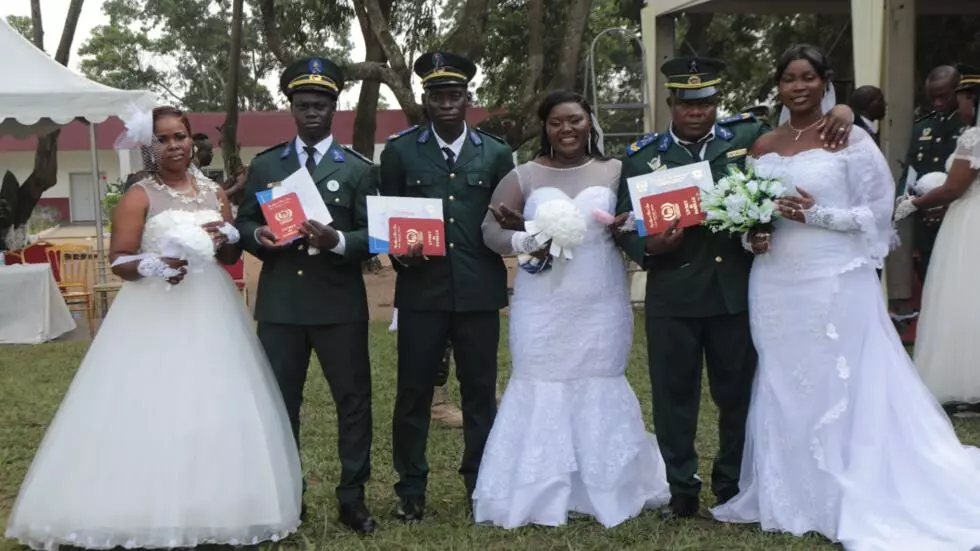 Image de Société. En Côte d'Ivoire, le mariage, symbole d'union et de célébration, s'est progressivement transformé en une lourde contrainte financière pour de nombreux couples. Dans un contexte où la société valorise de plus en plus les cérémonies grandioses et sophistiquées, nombreux sont ceux qui hésitent à franchir le pas. Face à cette réalité, des solutions innovantes émergent, comme les mariages collectifs organisés par des entreprises et des institutions, offrant ainsi une bouffée d'air frais aux jeunes couples désireux de se marier sans se ruiner. Ces événements collectifs, bien que ponctuels, constituent une réponse à un problème économique profond et soulèvent de nombreuses questions sur l'évolution des pratiques sociales et des priorités financières dans la société ivoirienne. Le mariage, une tradition coûteuse Le mariage en Côte d'Ivoire, comme dans de nombreuses sociétés, est un rite de passage significatif. Il symbolise l'engagement et la continuité des valeurs familiales. Cependant, au fil des années, cette institution s'est complexifiée et est devenue de plus en plus onéreuse. Si autrefois, un mariage civil était un acte simple, aujourd'hui, il est souvent accompagné de fêtes somptueuses, de réceptions fastueuses, et d'une série de dépenses incontournables, tant matérielles que symboliques. La demande d'une cérémonie à la hauteur des attentes familiales et sociales est un fardeau financier de plus en plus lourd à porter. De nombreuses familles, notamment celles issues des classes populaires, trouvent difficile de financer un mariage traditionnel qui peut parfois coûter des dizaines de millions de francs CFA. Les frais de mairie, les tenues, le banquet, les animations, les cadeaux, et les transports sont autant de dépenses auxquelles s'ajoutent parfois des exigences sociales pour que le mariage soit jugé acceptable aux yeux de la communauté. Dès lors, un grand nombre de jeunes couples renoncent à cette institution ou repoussent sans cesse la date de leur mariage. Pour pallier cette difficulté, certains acteurs économiques et sociaux ont choisi de mettre en place des mariages collectifs. L'objectif est simple : mutualiser les coûts tout en permettant aux jeunes couples de célébrer leur union dans des conditions dignes. Ce phénomène, bien qu'encore récent, prend de l'ampleur et s'ancre progressivement dans les mentalités comme une alternative sérieuse à l'organisation des mariages classiques. Parmi les institutions qui ont initié ces événements, la Société des Transports Abidjanais (Sotra) et la société Ivosep se distinguent en mettant à disposition leurs ressources pour soutenir les militaires, les fonctionnaires et les civils dans l'organisation de leur mariage. Un exemple frappant de cette dynamique a eu lieu récemment au sein du milieu militaire, où 280 personnes ont célébré leur mariage lors d'une cérémonie commune, financée et organisée par l'état-major des armées. Cette initiative permet de réduire significativement les coûts associés au mariage civil, tout en offrant aux militaires un soutien symbolique et matériel en ces moments particuliers de leur vie. Le mariage collectif organisé par les armées ivoiriennes est un modèle de pragmatisme social. Chaque couple vient accompagné de deux témoins, et après la lecture des articles du Code civil, l’officier d'état-civil procède à l’échange des consentements. Mais derrière la simplicité apparente de cette cérémonie, il y a un véritable soulagement pour de nombreux militaires qui, malgré leurs engagements et sacrifices pour la nation, n'ont pas toujours les moyens financiers de concrétiser leur union. Le sergent Modeste Nankou Djogo, père de quatre enfants, exprime bien cet état d’esprit : "Dieu merci, c'est vraiment arrivé. Je suis vraiment, vraiment heureux." Il raconte qu’il a attendu 27 ans avant de pouvoir officialiser son mariage, un délai lié à des problèmes d’emploi du temps, mais aussi aux contraintes financières. Pour lui, ce mariage collectif est une véritable délivrance. "C’est comme si un poids venait de disparaître", ajoute-t-il, soulignant combien le mariage représente un poids psychologique, autant qu’économique, dans une société où les attentes sociales sont élevées. Le financement de cette cérémonie par l'état-major, en collaboration avec le ministère de la Défense, a permis de rendre l'événement accessible à tous les militaires, sans qu'ils aient à s'endetter ou à sacrifier d’autres besoins familiaux. "Si ce n’était pas le cas, on aurait dû dépenser entre 2 à 2,5 millions de francs. Il faut payer la mairie, tous les frais, tout… Il y a beaucoup de choses qui sont requises", explique le sergent-chef Gbagbé, père de six enfants. Ce geste contribue non seulement à alléger les charges financières, mais aussi à renforcer la solidarité au sein de la communauté militaire. L’aspect économique et social des mariages collectifs Les mariages collectifs ne se contentent pas d’offrir une solution économique. Ils deviennent également un outil puissant de cohésion sociale. En permettant à des jeunes couples de se marier sans avoir à supporter seuls la pression des coûts, ces événements favorisent une forme d’égalité entre les différentes couches de la société. Ils participent à la réduction des inégalités sociales en offrant aux personnes des milieux modestes la possibilité d’aspirer à une cérémonie digne de ce nom, sans devoir recourir à des prêts ou à des sacrifices excessifs. Le sociologue Gnelbin Hlil, spécialiste des questions sociales en Côte d'Ivoire, souligne : "Ce sont les cérémonies qui coûtent cher, les fêtes, les réjouissances." Selon lui, un mariage doit avant tout être un acte symbolique et un engagement, et non un fardeau financier. Dans cette optique, l’initiative des mariages collectifs s’inscrit parfaitement dans une logique de solidarité et de soutien collectif, surtout dans un contexte économique difficile. Au-delà de l’aspect économique, les mariages collectifs s'inscrivent dans une démarche de soutien social. Le général Lassina Doubia, chef d’état-major des armées, met en lumière la précarité des veuves de militaires, qui souvent ne peuvent même pas prouver leur statut pour bénéficier des droits de succession et d’autres avantages. En offrant aux militaires l’opportunité de formaliser leur mariage dans de meilleures conditions, ces cérémonies permettent également de réduire les frustrations et les injustices sociales, tout en facilitant l’accès à certains droits sociaux. Le soutien financier et logistique apporté par l’état-major et le ministère de la Défense à ces mariages collectifs illustre la volonté des autorités de prendre en compte les réalités sociales de leurs citoyens, en particulier ceux qui, en raison de leur statut militaire, font face à des défis uniques. Cette démarche pourrait-elle inspirer d’autres secteurs de la société à adopter des pratiques similaires ?