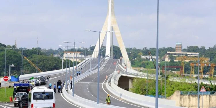 Image de Société. Le pont Alassane Ouattara, fierté architecturale d’Abidjan, va connaître des perturbations de circulation à partir du vendredi 7 mars. En effet, le ministre ivoirien de l’Équipement et de l’Entretien routier, Amédé Koffi Kouakou, a annoncé une fermeture partielle de l’ouvrage les week-ends, de 22h à 4h du matin, pour permettre le nettoyage du pylône. Ces travaux, qui s’étaleront sur trois à quatre week-ends consécutifs, visent à préserver la blancheur emblématique de cette structure de 108 mètres de haut. Alors que le pont est devenu un symbole de modernité et de connectivité pour la Côte d’Ivoire, cette opération soulève des questions sur la gestion des infrastructures urbaines et leur impact sur la vie des Abidjanais. Un nettoyage nécessaire pour préserver l’esthétique du pont Le pont Alassane Ouattara, inauguré en grande pompe le 12 août 2023 par le président Alassane Ouattara, est bien plus qu’un simple ouvrage de génie civil. Avec son pylône culminant à 108 mètres et ses haubans élégants, il incarne l’ambition de la Côte d’Ivoire de se positionner comme un leader régional en matière d’infrastructures modernes. Cependant, cette beauté architecturale nécessite un entretien rigoureux. « Ce pont est un bel ouvrage qui a une belle architecture. Et l’architecte a souhaité que l’ouvrage soit blanc », a rappelé le ministre Amédé Koffi Kouakou lors d’une récente visite sur le site. Le nettoyage du pylône, qui sera réalisé à l’aide de détergents spécifiques, est une opération délicate. Elle ne peut être effectuée en présence de trafic routier, d’où la décision de fermer partiellement le pont pendant les week-ends. « On va commencer le vendredi à 22h. On va fermer l’ouvrage jusqu’au lundi à 4h du matin sur trois à quatre week-ends pour que ce nettoyage puisse se faire. Ça veut dire qu’en semaine, l’ouvrage est ouvert 24h/24 », a précisé le ministre. Cette fermeture nocturne permettra aux équipes de travailler en toute sécurité et d’éviter tout risque pour les usagers. Impact sur la circulation et la vie des Abidjanais La fermeture partielle du pont Alassane Ouattara, bien que temporaire, aura des répercussions sur la circulation et la vie quotidienne des habitants d’Abidjan. Reliant les communes de Cocody et du Plateau, deux zones stratégiques de la capitale économique ivoirienne, le pont est un axe majeur pour les déplacements urbains. Les restrictions de circulation, bien que limitées aux week-ends, pourraient engendrer des embouteillages sur les itinéraires alternatifs, notamment sur le pont Henri Konan Bédié et les routes secondaires. Pour minimiser les désagréments, les autorités ont mis en place un plan de circulation détaillé, incluant des panneaux de signalisation et des équipes sur le terrain pour orienter les usagers. Cependant, certains habitants s’interrogent sur la fréquence et la durée de ces fermetures. « Est-ce que ces travaux vont devenir récurrents ? », s’interroge un automobiliste rencontré sur place. « Le pont est magnifique, mais il faut aussi penser à ceux qui doivent se déplacer la nuit pour travailler. » Par ailleurs, cette opération soulève des questions plus larges sur la gestion des infrastructures urbaines en Côte d’Ivoire. Alors que le pays investit massivement dans des projets d’envergure, comme le pont Alassane Ouattara, il est crucial de prévoir des plans d’entretien à long terme pour éviter des perturbations répétées. Un symbole de modernité et de connectivité Le pont Alassane Ouattara est bien plus qu’un simple pont. Il est devenu un symbole de la modernité et de la connectivité en Côte d’Ivoire. Inauguré en 2023, il a rapidement été adopté par les Abidjanais, qui le considèrent comme une prouesse technique et un atout pour le développement économique de la région. Avec ses lignes épurées et son éclairage nocturne spectaculaire, il attire également les touristes et les amateurs d’architecture. Cependant, cette structure emblématique doit également répondre à des enjeux pratiques. En reliant Cocody au Plateau, deux zones clés d’Abidjan, le pont facilite les déplacements et réduit les temps de trajet. Il contribue ainsi à désengorger le trafic dans une ville où les embouteillages sont souvent synonymes de stress et de perte de productivité. Mais pour que le pont continue de jouer ce rôle, il est essentiel de garantir son entretien. Les travaux de nettoyage actuels ne sont qu’une première étape. À terme, le ministère de l’Équipement et de l’Entretien routier devra mettre en place un plan de maintenance régulier pour préserver l’intégrité et l’esthétique de l’ouvrage. Une fois les travaux achevés, l’ouvrage sera probablement réceptionné et son entretien sera placé sous la responsabilité du département ministériel, a indiqué Amédé Koffi Kouakou. Les travaux de nettoyage du pylône du pont Alassane Ouattara soulignent l’importance de préserver les infrastructures urbaines tout en minimisant leur impact sur la vie des citoyens. Alors que la Côte d’Ivoire continue de se doter d’ouvrages modernes et ambitieux, la question de leur entretien et de leur gestion à long terme devient cruciale. Comment concilier esthétique et fonctionnalité ? Comment garantir que ces infrastructures continuent de servir les populations sans devenir une source de perturbations répétées ? Le pont Alassane Ouattara, avec ses lignes élégantes et son rôle central dans la connectivité d’Abidjan, est un exemple emblématique de ces défis. Alors que les travaux de nettoyage débutent, une question reste ouverte : comment la Côte d’Ivoire peut-elle s’inspirer de cette expérience pour mieux gérer ses futures infrastructures et en faire des atouts durables pour son développement ?