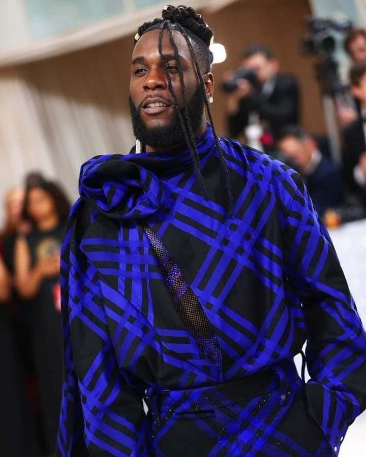 Deuxième Image de Célébrités. Le talentueux artiste chanteur Nigérian, Burna Boy, a eu l'honneur comme certains de ses compatriotes tels que Tems et Skepta, à être invité au prestigieux gala Met qui s'est tenu ce lundi 1er mai à New York. Il faut dire que le thème de ce gala était Karl Lagerfeld en hommage au célèbre homme de la mode décédé en 2019. Pour dire vrai, ce qui a attiré l'attention des uns et des autres chez Burna Boy c'est plutôt la tenue avec une traîne qu'à arborer la méga star africaine. Je vous laisse découvrir sa tenue et ne manquez pas de me laisser vos impressions.