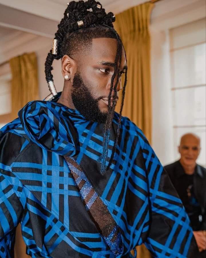 Troisième Image de Célébrités. Le talentueux artiste chanteur Nigérian, Burna Boy, a eu l'honneur comme certains de ses compatriotes tels que Tems et Skepta, à être invité au prestigieux gala Met qui s'est tenu ce lundi 1er mai à New York. Il faut dire que le thème de ce gala était Karl Lagerfeld en hommage au célèbre homme de la mode décédé en 2019. Pour dire vrai, ce qui a attiré l'attention des uns et des autres chez Burna Boy c'est plutôt la tenue avec une traîne qu'à arborer la méga star africaine. Je vous laisse découvrir sa tenue et ne manquez pas de me laisser vos impressions.