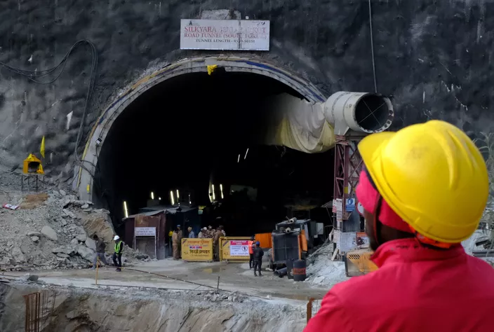 Image de Société. Onze jours se sont écoulés depuis l'effondrement d'un tunnel dans l'État d'Uttarakhand, en Inde, piégeant 41 ouvriers. Les équipes de sauvetage, composées d'ingénieurs et de secouristes, s'efforcent de forer un large tube d'acier à travers les décombres du tunnel sur une distance d'au moins 57 mètres de terre et de roches. Progression des Opérations de Sauvetage Mercredi dernier, les sauveteurs ont annoncé avoir réussi à forer les deux tiers des décombres du tunnel. Mahmood Ahmad, un responsable du ministère des Routes et des Autoroutes impliqué dans les opérations, a déclaré avec optimisme : « Je suis très heureux d'annoncer (...) que 39 mètres de forage ont été achevés. » Cependant, il a souligné que la section restante à forer représentait une phase critique. Espoirs et Défis Les autorités ont exprimé l'espoir d'obtenir de bonnes nouvelles dans les prochains jours, mais ont également souligné que les délais fournis étaient susceptibles d'être modifiés en raison de problèmes techniques, du terrain difficile de l'Himalaya et d'éventuelles urgences imprévues. Le ministre en chef de l'Uttarakhand, Pushkar Singh Dhami, a évoqué des « progrès positifs » sans fournir de détails spécifiques. Les Conditions Complexes de l'Himalaya Les opérations de sauvetage sont compliquées par le terrain difficile de l'Himalaya, caractérisé par des chutes de débris fréquentes. Les équipes doivent faire face à des pannes successives de machines de forage, ajoutant des défis supplémentaires à des opérations déjà délicates. La semaine dernière, une machine de forage a heurté des rochers, suspendant les opérations pendant plus de trois jours après qu'un craquement dans le tunnel a semé la panique parmi les équipes. Impact sur les Familles et la Communauté Pendant ce temps, les familles des ouvriers piégés attendent avec anxiété des nouvelles de leurs proches. La tension monte alors que l'attente prolongée suscite des préoccupations quant à la sécurité et au bien-être des travailleurs. Les autorités font tout leur possible pour assurer la transparence dans les communications tout en reconnaissant les défis auxquels elles sont confrontées. Perspectives d'Avenir Alors que les équipes de sauvetage font des progrès, la question cruciale demeure : pourront-elles atteindre les ouvriers piégés en toute sécurité ? La complexité des opérations, les conditions du terrain et les imprévus potentiels continuent de planer sur l'issue du sauvetage. La situation actuelle soulève des questions sur la sécurité des travaux de construction dans des régions géographiquement difficiles et met en lumière l'importance des mesures de prévention des accidents sur de tels sites. La Sécurité dans les Projets de Construction À mesure que les opérations de sauvetage se poursuivent, la nécessité d'évaluer les protocoles de sécurité dans les projets de construction similaires devient évidente. Des enquêtes post-sauvetage pour comprendre les causes de l'effondrement du tunnel et mettre en œuvre des mesures préventives pour éviter de tels incidents à l'avenir sont impératives. Comment les autorités et les entreprises de construction peuvent-elles renforcer les protocoles de sécurité dans des régions géographiquement difficiles pour prévenir de tels incidents à l'avenir ?