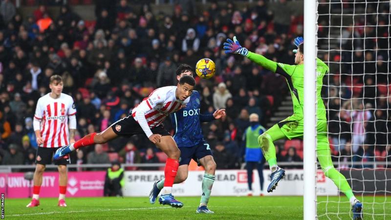 Image de Football. Le milieu de terrain adolescent Jobe Bellingham s'est une fois de plus imposé comme le héros de Sunderland, contribuant à leur victoire contre Leeds United et mettant fin à la série de sept matchs sans défaite de l'adversaire. Ce succès marquait la deuxième victoire consécutive en Championship sous la direction de l'entraîneur intérimaire, Mike Dodds, qui avait pris les rênes après le départ de l'ancien entraîneur Tony Mowbray. Leeds United, sous la direction de Daniel Farke, avait une forme redoutable, enregistrant trois victoires consécutives lors de leurs matchs précédents. L'équipe a présenté une menace offensive puissante, marquant huit buts lors de ces victoires. Cependant, Sunderland a exécuté un plan de match bien pensé pour neutraliser la puissance offensive de Leeds. Le moment décisif est survenu à 12 minutes de la fin lorsque Bellingham a courageusement dirigé le ballon dans le filet alors que le gardien de Leeds, Illan Meslier, tentait d'étouffer la menace. Les deux gardiens, Anthony Patterson pour Sunderland et Meslier pour Leeds, avaient auparavant réalisé des arrêts cruciaux, mettant en valeur leurs compétences et maintenant l'égalité dans le jeu. Une parade notable était le renversement de Patterson sur le coup franc brûlant de Crysencio Summerville, tandis que Meslier a fait preuve de son agilité avec une paume tendue pour nier la tête de Jenson Seelt qui se dirigeait vers le but. La clearance de Trai Hume sur la ligne en fin de match a illustré la détermination de Sunderland à empêcher Leeds de récupérer un point. Les scènes à la fin du match reflétaient le grand respect dans lequel Dodds est tenu par les supporters de Sunderland. Ayant fait partie de l'encadrement sous Mowbray, Dodds avait été impliqué dans les préparatifs avant et après le départ de Mowbray. Son dispositif tactique a efficacement nié l'espace et la liberté au quatuor offensif de Leeds, y compris les joueurs de couloir influents Daniel James et Summerville. Sunderland a reproduit la formation réussie et les ajustements en cours de match de leur précédent match contre West Bromwich Albion. Niall Huggins et Hume ont marqué étroitement les couloirs, tandis que le trio central composé de Dan Neil, Bellingham et Abdoullah Ba a pressé de manière incessante, perturbant le duo de milieu de terrain de Leeds, composé de Glen Kamara et Ethan Ampadu. Malgré les discussions sur le besoin d'un attaquant, la performance impactante de Bellingham en position offensive s'est avérée cruciale. Le match a été par moments un chef-d'œuvre défensif, mais il est resté ouvert et divertissant, les deux équipes créant d'excellentes occasions. Le coup franc de Summerville, la frappe courbée de Spence et le blocage de Bellingham sur le tir puissant de Piroe ont ajouté à l'excitation. Jack Clarke de Sunderland, face à son ancien club, s'est avéré être une épine dans le pied de Leeds, obligeant Archie Gray à commettre une faute qui lui a valu un carton jaune et fournissant une menace persistante. Bien que Leeds ait manqué une quatrième victoire consécutive pour la première fois depuis leur campagne en Premier League 2020-2021, l'équipe a montré les qualités d'un prétendant à la promotion. Des résultats comme celui-ci suggèrent que Sunderland, sous la direction de Dodds, pourrait également être en lice pour la promotion. Lors d'une interview après le match, l'entraîneur intérimaire de Sunderland, Mike Dodds, a exprimé sa joie pour les joueurs, le personnel et les supporters. Il a salué l'éthique de travail de l'équipe, soulignant l'exécution réussie du plan de match. Dodds a mis en avant la performance défensive remarquable contre une équipe de qualité de Premier League, limitant les occasions adverses à un nombre minimal. L'entraîneur de Leeds, Daniel Farke, a salué le formidable effort défensif de Sunderland et les a félicités pour avoir mis en œuvre une stratégie qui incluait un changement de formation en 5-3-2. Malgré une domination de la possession, Farke a noté que son équipe manquait de netteté et de précision dans les moments cruciaux, les empêchant de trouver la solution décisive. Alors que la question des chances de promotion de Sunderland se profile, on se demande comment l'acuité tactique de Mike Dodds et la forme actuelle de l'équipe façonneront leur trajectoire en Championship. Sunderland peut-il maintenir ce niveau de performance et rivaliser avec des budgets de Premier League pour s'assurer une place parmi les prétendants à la promotion ?