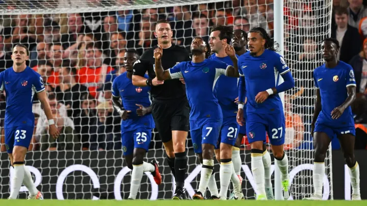 Image de Football. Le triomphal 3-2 de Chelsea sur Luton Town à Kenilworth Road s'est déroulé comme un spectacle captivant, marquant un tournant significatif pour les Blues dans leur campagne à l'extérieur de la Premier League. Le choc très attendu a non seulement mis en valeur la résilience de l'équipe, mais a également soulevé des questions intrigantes sur leurs récentes difficultés à l'extérieur. Le match a commencé avec Chelsea, armé de son effectif coûteusement assemblé, cherchant à inverser une tendance décourageante de quatre défaites consécutives à l'extérieur en Premier League. Les enjeux étaient élevés, et la pression était palpable alors qu'ils affrontaient une équipe de Luton déterminée à remporter une victoire décisive sur son terrain. À la 12e minute, Cole Palmer a donné le ton avec une finition clinique, profitant d'une faille dans la défense de Luton. L'avance précoce a donné à Chelsea un coup de fouet nécessaire, signalant leur intention de dominer la rencontre. Au fur et à mesure que le match progressait, la puissance offensive des Blues s'est manifestée, et à la 37e minute, Noni Madueke a montré son talent en concluant une action magnifiquement orchestrée, doublant l'avance de Chelsea. La première mi-temps s'est conclue avec Chelsea fermement en contrôle, menant 2-0. La seconde mi-temps, cependant, s'est déroulée avec une intensité et un drame encore plus grands. Palmer, une fois de plus, a montré son talent de buteur à la 70e minute, contournant le gardien pour marquer son deuxième but de la soirée et portant l'avance de Chelsea à 3-0. À ce stade, il semblait que Chelsea avait réussi à surmonter ses difficultés à l'extérieur et était en route pour une victoire convaincante. Cependant, la nature imprévisible du football est venue au premier plan lorsque l'ancien milieu de terrain de Chelsea, Ross Barkley, maintenant joueur de Luton, a marqué de la tête sur un corner d'Alfie Doughty à la 80e minute. Soudain, ce qui semblait être une victoire sans problème s'est transformé en une rencontre plus disputée. Le drame a encore monté d'un cran lorsque Elijah Adebayo a trouvé le filet à la 87e minute, réduisant l'écart à un seul but. Alors que le temps s'écoulait, Luton a lancé une dernière offensive, cherchant désespérément à égaliser. Malgré leurs efforts vaillants, les Hatters sont tombés court et Chelsea est sorti victorieux avec un score de 3-2. Alors que la poussière retombe sur cette rencontre palpitante, il est impératif d'explorer les implications et les récits qui ont émergé de ce match. Tout d'abord, la capacité de Chelsea à résister au retour tardif de Luton soulève des questions sur la résilience défensive de l'équipe et sa force mentale globale dans des situations difficiles. Comment cette victoire âprement disputée impactera-t-elle la confiance de Chelsea, en particulier dans les matchs à l'extérieur ? Le projecteur se tourne également vers les performances individuelles, avec l'excellente prestation de Cole Palmer qui lui vaut des éloges. Sa performance exceptionnelle annonce-t-elle un tournant potentiel dans sa carrière à Chelsea, et comment cela pourrait-il influencer la dynamique de l'équipe à l'avenir ? De plus, les contributions de Noni Madueke, qui a montré sa puissance offensive avec un but sublime, ajoutent une autre dimension au récit. Quelle est l'importance de la forme de Madueke pour la stratégie offensive de Chelsea, et peut-il offrir de telles performances de manière constante ? D'un autre côté, la remontée pleine d'ardeur de Luton, bien qu'elle ait échoué de peu, soulève des questions sur leur résilience et leur capacité à rivaliser avec des équipes de premier plan. Comment peuvent-ils capitaliser sur les aspects positifs de ce match pour améliorer leur performance globale en Premier League ? Dans le contexte plus large de la Premier League, ce match incite à la réflexion sur la nature compétitive de la ligue et l'imprévisibilité qui fait de chaque rencontre un spectacle. Alors que Chelsea assure une victoire cruciale à l'extérieur, la question qui résonne est de savoir si cela marque un tournant dans leur forme à l'extérieur ou si des défis subsistent. Alors que les fans et les analystes dissèquent les nuances de cette rencontre passionnante, la question persistante est la suivante : quelles leçons peuvent tirer Chelsea et Luton de ce match, et comment cela façonnera-t-il leurs parcours respectifs en Premier League ? Les réponses à ces questions se dévoileront sans aucun doute au fil des prochains matches, ajoutant de nouvelles couches au récit captivant de la saison de Premier League.