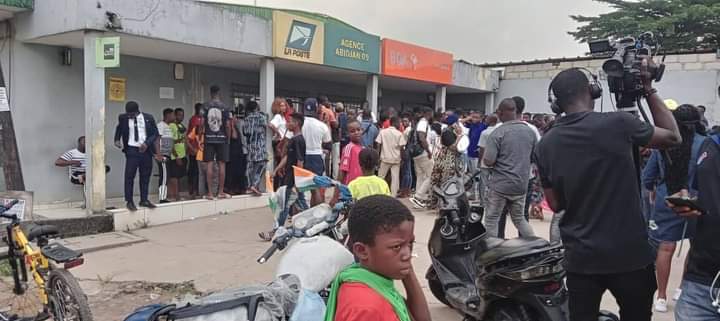 Troisième Image de Football. La poste d'Adjamé 220 est bien plus qu'un simple lieu de service postal dans la vie quotidienne des habitants d'Abidjan, Côte d'Ivoire. C'est un point névralgique où la passion pour le football et le soutien inébranlable envers l'équipe nationale, les Éléphants, se manifeste de manière frappante. L'effervescence qui règne à cet endroit est indéniablement liée à l'enthousiasme des supporters qui se pressent pour s'offrir des tickets en vue du prochain match tant attendu. Les rues animées d'Adjamé servent de toile de fond à cette scène dynamique, où les supporters se rassemblent avec l'espoir palpable de voir leurs héros nationaux fouler le terrain. L'atmosphère est électrique, chargée d'une énergie positive qui unit les individus autour d'une cause commune : le soutien fervent à l'équipe de football nationale. Les discussions enflammées sur les performances passées et les pronostics pour le prochain match résonnent dans l'air, créant un sentiment d'unité parmi les supporters. À l'intérieur de la poste d'Adjamé 220, les guichets habituellement dédiés aux services postaux se transforment en points de vente improvisés pour les billets du match des Éléphants. Les employés de la poste, habitués à traiter des colis et des lettres, se retrouvent désormais à jouer un rôle crucial dans la distribution des billets et à gérer l'afflux constant de supporters passionnés. La transition temporaire de cet espace postal en un centre de distribution de billets de football souligne l'importance culturelle du sport dans la vie quotidienne des habitants. Les supporters, vêtus des couleurs vives de l'équipe nationale, forment une file d'attente qui s'étend bien au-delà de l'entrée de la poste. Le brouhaha joyeux des discussions et des chants de soutien crée une ambiance festive, transformant temporairement la poste en un lieu de célébration collective. Les enfants, les jeunes et les adultes partagent cet esprit communautaire, renforçant ainsi les liens sociaux au-delà des différences individuelles. Certains supporters arrivent munis de drapeaux, de tambours et d'autres accessoires festifs pour exprimer leur dévouement envers l'équipe nationale. Ces éléments visuels ajoutent une dimension artistique à l'événement, transformant la poste en une galerie temporaire où les symboles nationaux et les expressions créatives des supporters convergent pour célébrer l'identité collective. Les moments de tension surviennent lorsque la demande de billets dépasse l'offre disponible. Des discussions animées et des négociations passionnées éclatent entre les supporters déterminés à obtenir leur précieux sésame pour le match à venir. Certains font preuve de créativité pour persuader les autres de céder leur place dans la file d'attente, tandis que d'autres partagent des anecdotes mémorables liées à leur passion pour les Éléphants. Ces interactions ajoutent une dimension humaine à l'expérience, soulignant l'impact émotionnel profond que le football a sur la vie des supporters. Les réseaux sociaux amplifient encore l'excitation palpable à la poste d'Adjamé 220. Des photos et des vidéos des supporters attendant patiemment leurs billets inondent les plateformes en ligne, créant une véritable frénésie virale. Les hashtags liés au match deviennent des tendances locales, renforçant la connectivité numérique entre les supporters et étendant l'expérience au-delà des limites physiques de la poste. En conclusion, la poste d'Adjamé 220 se transforme en un théâtre vibrant où la passion pour le football et le soutien indéfectible envers l'équipe nationale des Éléphants transcendent les fonctions habituelles de cet espace. C'est un lieu où la communauté se rassemble, où les liens sociaux se renforcent et où l'excitation pour le prochain match crée une atmosphère unique et mémorable. Au-delà des transactions postales ordinaires, la poste d'Adjamé 220 devient un symbole vivant de la façon dont le sport peut fusionner avec la vie quotidienne pour créer des moments d'unité et de célébration.