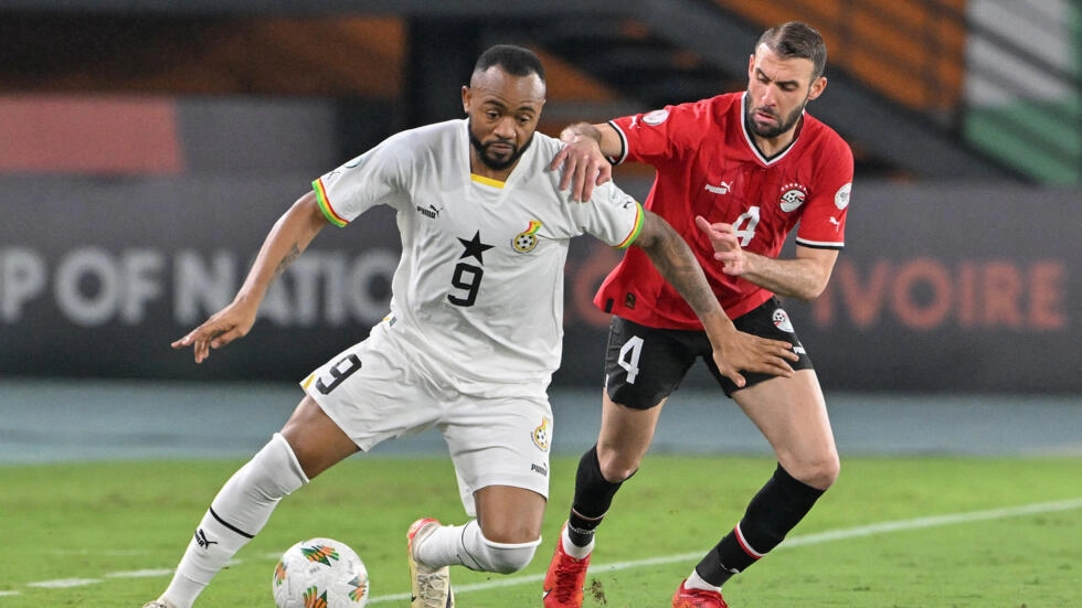 Image de Football. Le match entre le Ghana et l'Égypte lors de la Coupe d'Afrique des Nations 2024 à Abidjan, s'est soldé par un match nul 2-2, un résultat qui laisse les deux équipes dans une situation délicate dans leur quête de qualification pour les phases suivantes du tournoi. Le match, marqué par une première période terne et la sortie sur blessure de la star égyptienne Mohamed Salah, a vu le Ghanéen Mohammed Kudus briller, devenant un élément clé dans le jeu des Black Stars. La première mi-temps, dominée par l'ennui, a été bouleversée dans ses derniers instants. Mohammed Kudus, de retour de blessure, a débloqué la situation pour le Ghana en marquant un but juste avant la pause. La sortie de Salah, visiblement touché à la cuisse, a été un coup dur pour l'Égypte, qui perdait ainsi son capitaine et joueur clé. L'Égypte, troublée mais pas abattue, a réagi en seconde mi-temps. Bien que privée de son joueur vedette, l'équipe a montré des signes de réveil, avec notamment une occasion notable sur un coup franc. Cependant, c'est une erreur du Ghanéen Inaki Williams qui a permis à l'Égypte d'égaliser par Omar Marmoush. La réponse du Ghana ne s'est pas fait attendre, Kudus marquant son deuxième but peu après pour redonner l'avantage à son équipe. Le match s'est intensifié, avec l'Égypte poussant pour revenir au score. Ce fut le cas grâce à une nouvelle erreur ghanéenne, cette fois de la part du remplaçant Osman Bukari, qui a perdu le ballon au profit de Trezeguet. Ce dernier a servi Mostafa Mohamed pour l'égalisation. Ce résultat 2-2 reflète une confrontation équilibrée mais également une occasion manquée pour les deux équipes. Le Ghana, après sa défaite initiale contre le Cap-Vert, devait impérativement gagner pour se relancer dans le tournoi. L'Égypte, de son côté, cherchait à se racheter après son match nul contre le Mozambique. Ainsi, les deux équipes se trouvent dans une position délicate, devant remporter leur prochain match pour espérer se qualifier. Mohammed Kudus, grâce à sa performance remarquable, a prouvé qu'il est un élément vital pour le Ghana. Sa capacité à transformer le jeu et à marquer dans des moments clés pourrait être déterminante pour la suite du tournoi pour les Black Stars. En revanche, l'Égypte doit trouver des solutions en l'absence de Mohamed Salah, sa star incontestée. Les deux équipes vont aborder leur troisième match avec la pression de devoir gagner pour se qualifier. Ce scénario met en lumière l'importance de chaque match dans un tournoi tel que la Coupe d'Afrique des Nations, où chaque point peut faire la différence entre une qualification et une élimination précoce. Le Ghana et l'Égypte, avec leur riche histoire dans le football africain, savent que l'atteinte des phases finales est un minimum attendu par leurs supporters. La performance de Mohammed Kudus pour le Ghana et la capacité de l'Égypte à s'adapter sans Mohamed Salah seront cruciales dans leurs prochaines rencontres. Ces équipes, dotées de talents individuels exceptionnels, doivent maintenant faire preuve de cohésion et de détermination pour surmonter les défis à venir. En conclusion, ce match nul 2-2 entre le Ghana et l'Égypte lors de la CAN 2024 à Abidjan soulève une question importante pour les deux équipes : comment peuvent-elles utiliser cette expérience pour se renforcer et assurer une performance optimale lors de leurs matchs décisifs à venir, et quelle stratégie devraient-elles adopter pour maximiser leurs chances de qualification tout en surmontant leurs faiblesses actuelles ?