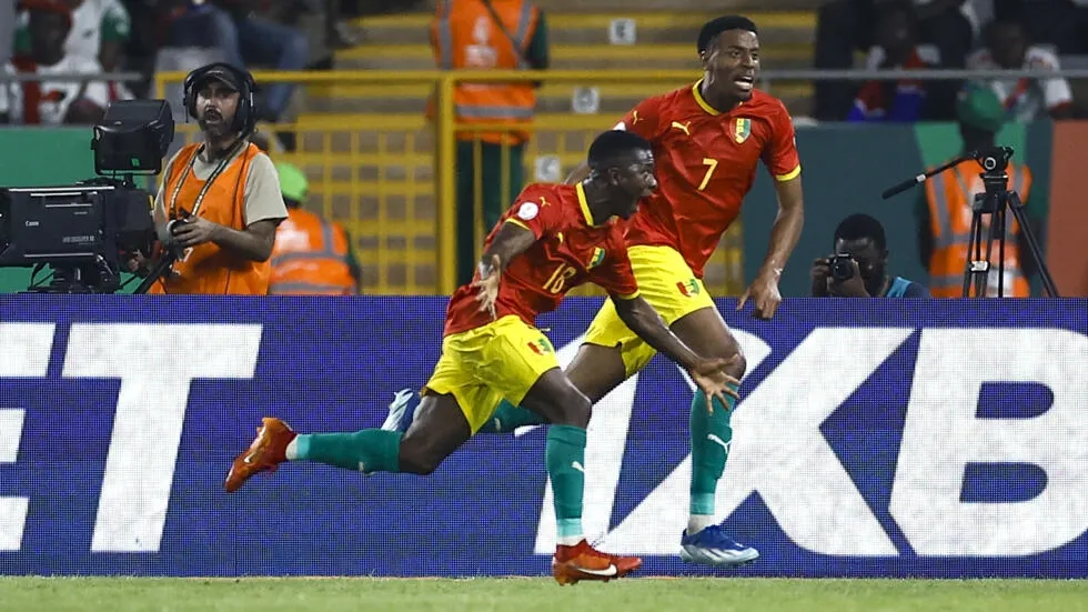 Image de Football. L'explosion de joie guinéenne à Yamoussoukro, après une victoire cruciale contre la Gambie (1-0), est le reflet d'une équipe qui, malgré des défis et des obstacles, continue de démontrer sa résilience et son esprit combatif dans cette CAN 2024. Cette victoire symbolise non seulement un pas de géant vers les huitièmes de finale, mais aussi l'affirmation du Syli National comme une force à ne pas sous-estimer dans le football africain. La rencontre, qui semblait s'acheminer vers un match nul sans buts, a été transcendée par un éclair de génie, un geste décisif qui a changé le cours de la partie. Ce moment, capturé dans un élan de passion et de technique, illustre la beauté et l'imprévisibilité du football. Les supporters guinéens, vêtus de rouge, jaune et vert, ont vibré au rythme des performances de leurs joueurs, transformant le stade en une mosaïque de couleurs et d'émotions. En revanche, pour la Gambie, cette défaite est une pilule amère à avaler. Après un parcours impressionnant lors de la précédente édition, les attentes étaient élevées. Cette rencontre était une opportunité pour eux de montrer qu'ils ne sont pas une étoile filante dans le paysage footballistique africain. Malgré leur défaite, l'esprit combattif et la qualité du jeu présenté par les Scorpions restent des points positifs à retenir. Analysons plus en profondeur les stratégies déployées par les deux équipes. La Guinée, sous la houlette de leur entraîneur, a démontré une capacité d'adaptation et une intelligence tactique. L'accent mis sur une défense solide, couplée à des attaques rapides et précises, a porté ses fruits. Leur jeu, basé sur la possession et la patience, a finalement craqué la défense gambienne. Du côté gambien, malgré la défaite, il y a des enseignements à tirer. Leur capacité à maintenir une pression constante et à créer des occasions montre qu'ils ont le potentiel pour surprendre de grandes équipes. L'entraineur gambien doit maintenant se concentrer sur la manière de transformer cette capacité en résultats concrets. En regardant vers l'avenir, la Guinée se prépare maintenant pour son dernier match de groupe, qui déterminera son sort dans le tournoi. Avec cette victoire, le moral de l'équipe est au beau fixe, et la confiance règne dans le camp guinéen. Pour la Gambie, il s'agit de rebondir et de tirer les leçons de cette défaite pour continuer à progresser dans le football africain et international. Cette rencontre, au-delà de son résultat, est une célébration du football africain, avec ses hauts et ses bas, ses moments de joie et de tristesse. Elle illustre la passion, le talent et l'esprit de compétition qui animent les nations participant à cette prestigieuse compétition continentale. En conclusion, cette victoire de la Guinée contre la Gambie pose une question cruciale pour l'avenir du football africain : comment les équipes moins cotées peuvent-elles continuer à défier les géants du continent et surprendre sur la scène internationale ?