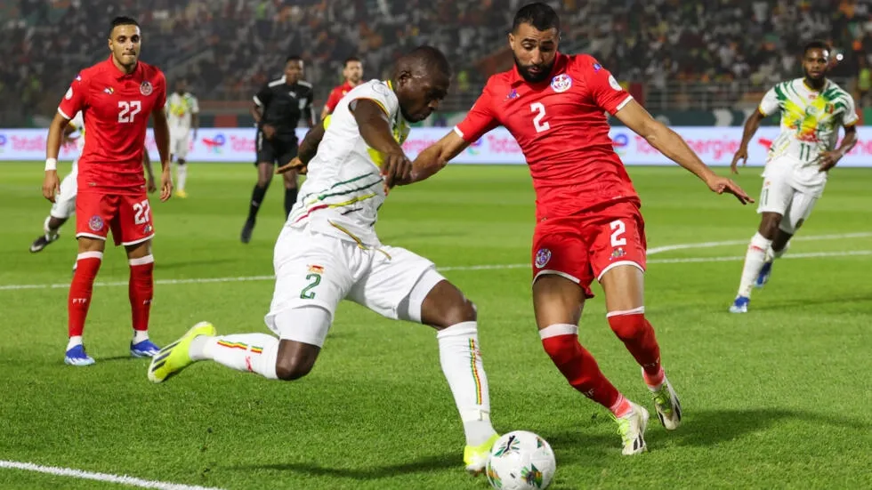 Image de Football. Le match entre le Mali et la Tunisie lors de la Coupe d'Afrique des Nations 2024 à Korhogo, qui s'est terminé sur un score de 1-1, a laissé les deux équipes dans des situations contrastées. Le Mali, avec quatre points après deux matchs, se rapproche d'une qualification, mais n'est pas encore assuré de passer en huitièmes de finale. D'un autre côté, la Tunisie se trouve dans une position précaire avec seulement deux points, rendant leur prochain match contre l'Afrique du Sud crucial pour leur survie dans le tournoi. La première mi-temps a été un spectacle palpitant, avec les deux équipes se livrant un duel intense. Les Maliens, montrant une supériorité dans le jeu, semblaient sur la voie de la qualification anticipée. L'ouverture du score par Lassine Sinayoko, avec une frappe croisée qui a trouvé le chemin des filets, a donné l'impression que les Aigles du Mali pourraient dominer le match. Cependant, la Tunisie a réagi rapidement, grâce à un but d'Hamza Rafia suite à un centre d'Ali Abdi, illustrant leur capacité à revenir dans le jeu. Le Mali a continué de pousser en seconde période, mais a été frustré par son incapacité à cadrer ses tirs, malgré plusieurs occasions en or. Le manque de précision dans les moments cruciaux a été symbolisé par la tentative manquée de Sinayoko en fin de match. Cela a souligné une certaine inefficacité offensive qui pourrait leur coûter cher dans les matchs à venir. La Tunisie, quant à elle, a montré un esprit de combat malgré ses limites techniques évidentes. Leur jeu, bien que manquant de fluidité, a été suffisant pour arracher un point précieux. Cependant, leur performance globale soulève des questions sur leur capacité à progresser dans le tournoi, surtout face à des adversaires potentiellement plus coriaces. Le match a également été marqué par des moments intenses, y compris une collision spectaculaire impliquant le gardien tunisien Bechir Ben Said, qui a nécessité une pause médicale. Ces incidents ont ajouté du drame à un match déjà chargé d'enjeux. Alors que le Mali peut se sentir frustré de ne pas avoir scellé sa qualification, il garde son destin entre ses mains. Pour la Tunisie, le défi est plus grand : ils doivent non seulement gagner leur dernier match de groupe contre l'Afrique du Sud, mais également espérer que d'autres résultats leur soient favorables. Ce match nul laisse plusieurs questions en suspens. Le Mali pourra-t-il surmonter ses problèmes d'efficacité pour assurer sa place en huitièmes de finale ? La Tunisie, quant à elle, peut-elle trouver la formule gagnante pour rester dans la compétition ? Leur prochain match contre l'Afrique du Sud déterminera leur destin, mais une chose est sûre : la pression est à son comble. Dans quelle mesure les performances des équipes dans les prochains matchs influenceront-elles leur trajectoire dans le tournoi et quelles leçons peuvent-elles tirer de ce match nul ?