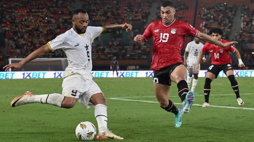 Image de Football. Le dernier match de poule du groupe B de la CAN 2024 offre une trame digne des grands tournois de football. Chaque équipe, à part le Cap-Vert déjà qualifié, se trouve à un carrefour décisif de son parcours, avec des implications qui dépassent la simple qualification pour les huitièmes de finale. L'Égypte et son Défi sans Salah Les Pharaons, avec deux points, sont face à un défi majeur : gagner sans leur star Mohamed Salah, blessé. Cette absence soulève des questions sur la capacité de l'équipe à maintenir son niveau de performance. Le match contre le Cap-Vert, pourtant sans enjeu pour ces derniers, prend une dimension critique pour l'Égypte. La pression est immense, pas seulement pour gagner, mais pour prouver qu'ils peuvent exceller même sans leur joueur phare. Le Ghana et le Mozambique : Une Lutte Acharnée Le Ghana et le Mozambique, avec un seul point chacun, se trouvent dans une situation précaire. Leur affrontement direct est plus qu'un simple match : c'est une bataille pour la survie dans le tournoi. Le retour de Mohammed Kudus pour le Ghana pourrait être un facteur clé, apportant une nouvelle dynamique à l'équipe. Quant au Mozambique, sa confiance semble intacte, mais est-ce suffisant pour renverser le cours des événements ? Les Enjeux du Dernier Jour Ce dernier jour de matchs dans le groupe B est riche en enjeux. Non seulement il déterminera qui avance dans le tournoi, mais il testera également la résilience et la capacité d'adaptation des équipes face à la pression et aux attentes. Pour l'Égypte, le Ghana et le Mozambique, c'est une opportunité de démontrer leur force de caractère et leur compétence tactique sous pression. Implications au-delà du Terrain Les résultats de ces matchs auront des implications bien au-delà des huitièmes de finale. Ils pourraient influencer la confiance des équipes, leur cohésion et même l'avenir de leurs entraîneurs. Les joueurs, particulièrement ceux qui prennent la place de figures absentes comme Mohamed Salah, ont l'occasion de briller et de se faire un nom sur la scène internationale. Perspectives pour les Supporters et les Analystes Pour les supporters, ces matchs sont un mélange d'excitation et d'anxiété. Chaque action sur le terrain peut déclencher une vague d'émotions. Les analystes, quant à eux, auront l'occasion d'évaluer les stratégies sous pression et la gestion des joueurs dans des situations critiques. L'Influence de la Chance et du Destin Bien que la stratégie et les compétences soient cruciales, le facteur chance joue également un rôle important. Un but chanceux, une décision d'arbitrage controversée ou un moment de génie peuvent changer le cours d'un match et, par extension, de tout un tournoi. Réflexion sur l'Impact du Football Ce scénario met en lumière l'impact du football non seulement comme sport, mais aussi comme phénomène culturel et social. Il unit les gens, suscite des passions et crée des moments inoubliables. Alors que le groupe B de la CAN 2024 s'achemine vers un dénouement dramatique, les équipes doivent non seulement affronter leurs adversaires sur le terrain, mais aussi gérer les attentes et la pression. C'est une preuve que le football, au-delà d'être un jeu, est un miroir des qualités humaines : courage, persévérance, et l'art de triompher face à l'adversité. Comment ces moments de pression intense dans des tournois comme la CAN influencent-ils la perception du football et ses joueurs dans le monde entier, et quels enseignements peut-on en tirer pour la vie au-delà du terrain ?