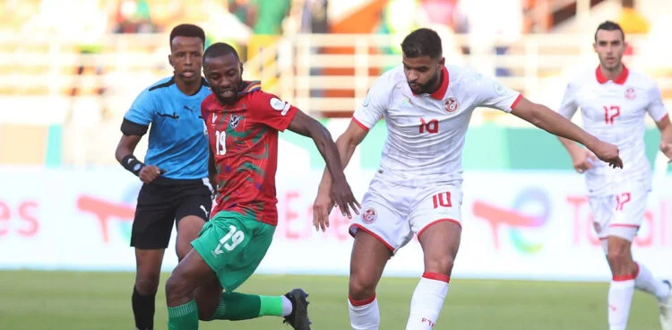 Image de Football. L'histoire de la Namibie dans la Coupe d'Afrique des Nations (CAN) 2024 est un conte de fées du football moderne. Avec une perspective historique de qualification pour les huitièmes de finale, la Namibie, surnommée les Brave Warriors, fait face à un défi de taille contre le Mali, une équipe déjà qualifiée et réputée pour sa force sur le continent africain. Ce match, au-delà d'être une simple rencontre sportive, symbolise les rêves et les aspirations d'une nation entière. Défier les Probabilités La Namibie, en dépit de son statut de petite nation footballistique, a démontré qu'elle pouvait surprendre. Sa victoire contre la Tunisie, un géant du football africain, a été un choc pour beaucoup et a servi de catalyseur pour la confiance de l'équipe. Cependant, la défaite sévère contre l'Afrique du Sud a montré les défis auxquels elle est confrontée. Malgré cela, le coach Collin Benjamin et son équipe restent positifs, prêts à rebondir et à affronter le Mali avec détermination et espoir. Une Équipe Soudée Le capitaine Peter Shalulile souligne l'importance de l'esprit d'équipe et de la fraternité. C'est cette unité qui pourrait être la clé de leur succès. L'équipe ne repose pas uniquement sur les épaules d'un seul joueur, mais sur la force collective et la cohésion de l'ensemble de l'équipe. Respect Mutuel L'approche respectueuse du Mali envers la Namibie témoigne de la nature imprévisible et ouverte de la CAN 2024. Le sélectionneur malien Éric Chelle reconnaît la qualité de jeu de la Namibie et son identité unique sous la houlette d'un bon coach. De même, le défenseur malien Sikou Niakaté exprime son anticipation et son respect pour l'équipe namibienne, reconnaissant que chaque équipe a sa propre valeur dans le tournoi. L'Identité de Jeu de la Namibie La Namibie a montré une identité de jeu distincte, mélangeant intensité et stratégie. Leur performance contre la Tunisie a démontré leur capacité à exploiter les faiblesses des adversaires et à jouer avec cœur. Face au Mali, ils devront non seulement maintenir cette intensité, mais aussi adapter leur jeu pour contrer les forces de leur adversaire. La Place du Football dans le Cœur des Nations Pour la Namibie, cette CAN n'est pas seulement une question de football ; c'est une question de fierté nationale. Le succès de l'équipe peut avoir un impact profond sur le moral et l'unité du pays, inspirant les jeunes et unissant les gens autour d'un objectif commun. L'Influence des Entraîneurs La dynamique entre les entraîneurs, Collin Benjamin pour la Namibie et Éric Chelle pour le Mali, est également cruciale. Leurs décisions tactiques, leur capacité à motiver les joueurs et à s'adapter en cours de match seront déterminantes pour le résultat final. La CAN, un Miroir de l'Afrique La CAN est bien plus qu'un tournoi de football ; c'est une célébration de la diversité culturelle et sportive de l'Afrique. Chaque match est une occasion de mettre en avant les différentes cultures, histoires et talents qui composent ce continent dynamique. L'Importance du Mental Le football est autant un jeu mental que physique. Pour la Namibie, le défi sera de surmonter la pression et de jouer sans crainte, malgré les enjeux élevés. C'est dans ces moments que les vrais caractères se révèlent et que les héros sont nés. Le Rôle des Supporters Les supporters namibiens jouent un rôle crucial. Leur soutien, leur passion et leur foi en l'équipe peuvent être un facteur motivant supplémentaire pour les joueurs. L'énergie qu'ils apportent peut transcender les performances sur le terrain. Alors que la Namibie se prépare à affronter le Mali, elle ne joue pas seulement pour une place dans les huitièmes de finale. Elle joue pour écrire une nouvelle page de son histoire footballistique, pour inspirer une nation et pour prouver que dans le football, tout est possible. Comment une performance exceptionnelle dans un tournoi comme la CAN peut-elle influencer et transformer le paysage du football dans un pays comme la Namibie, et quel impact cela pourrait-il avoir sur le développement du sport à l'échelle nationale ?