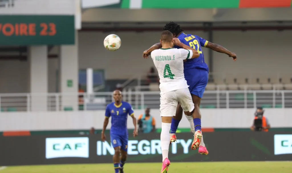 Image de Football. L'histoire de la Coupe d'Afrique des Nations (CAN) 2024 continue de s'écrire avec des moments de bravoure, de déception, et des surprises inattendues. Au cœur de cette épopée sportive se trouve la rencontre entre la RD Congo et la Tanzanie, un match crucial pour les deux équipes, qui s'est déroulé le mercredi 24 janvier au stade Amadou Gon Coulibaly de Korhogo. Ce match, décisif pour la qualification en huitièmes de finale, a été marqué par des stratégies défensives fortes et un manque de concrétisation en attaque. Les Léopards de la RD Congo, ayant adopté une formation en 4-2-3-1, ont cherché à imposer leur rythme dès les premières minutes. Face à eux, les Taifa Stars de Tanzanie, alignés en 4-1-4-1, ont fait preuve d'une organisation défensive rigoureuse. Ce choc des styles a donné lieu à une première mi-temps animée, mais sans but. Les attaquants congolais, tels que Wissa et Mayele, ont multiplié les tentatives, mais se sont heurtés à un mur en la personne de Manula, le gardien tanzanien, qui a réalisé plusieurs arrêts décisifs. En parallèle, la Tanzanie a tenté de surprendre son adversaire par des frappes lointaines et quelques incursions offensives, mais sans grand succès. Le match a donc oscillé entre l'offensive congolaise et la résistance tanzanienne, avec une première période se terminant sur un score nul de 0-0. La seconde mi-temps a repris sur un rythme similaire, avec la RD Congo dominant la possession du ballon mais incapable de percer la défense adverse. Les changements effectués par les deux équipes n'ont pas suffi à débloquer la situation. Malgré quelques tentatives audacieuses de Wissa, la Tanzanie a réussi à garder ses cages inviolées. Finalement, le match s'est soldé par un 0-0, un résultat qui a permis à la RD Congo de se qualifier pour les huitièmes de finale grâce à la victoire du Maroc sur la Zambie dans l'autre match du groupe. La Tanzanie, quant à elle, a été éliminée malgré une prestation défensive remarquable. Ce résultat soulève des questions sur l'efficacité offensive des équipes et l'importance des stratégies défensives dans les tournois majeurs. En conclusion, cette rencontre a été un exemple parfait de la tension et de l'enjeu que représente chaque match dans un tournoi de cette envergure. La RD Congo avance dans la compétition, mais doit repenser son approche offensive pour aller plus loin. La Tanzanie, malgré son élimination, peut tirer fierté de sa performance défensive. Alors que la CAN 2024 continue de dérouler ses surprises et ses moments de gloire, une question se pose : comment les équipes peuvent-elles trouver l'équilibre parfait entre une défense solide et une attaque efficace dans les compétitions internationales de haut niveau ?